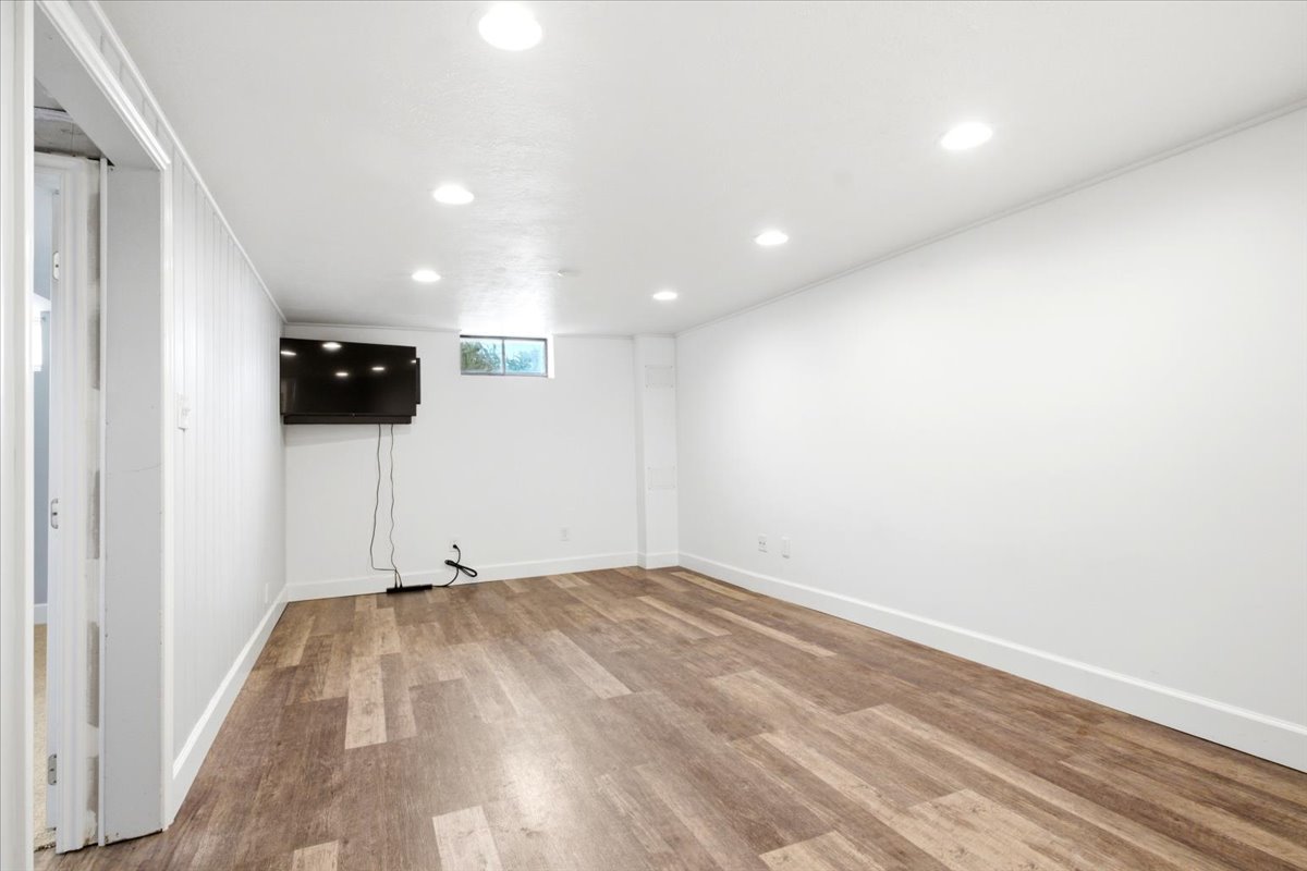 Spacious room featuring wood-finish flooring, recessed lighting, and a window