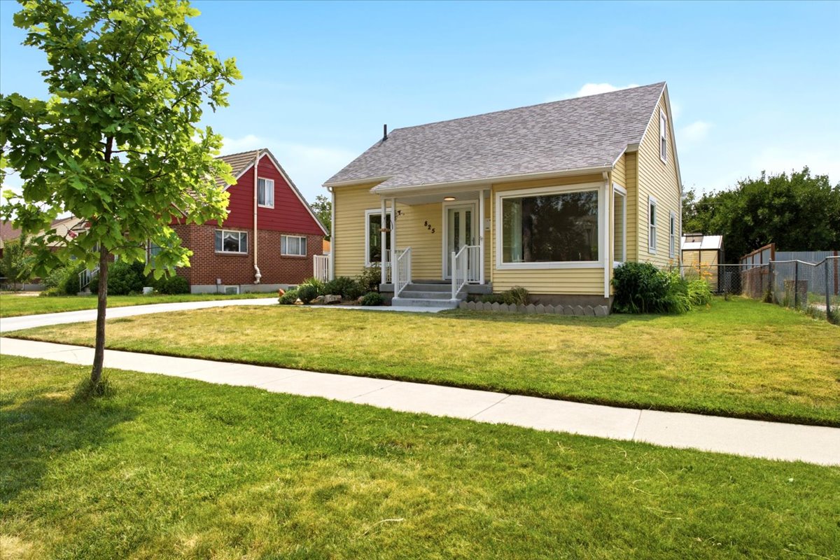 Charming light yellow siding exterior with a contrasting grey shingle roof