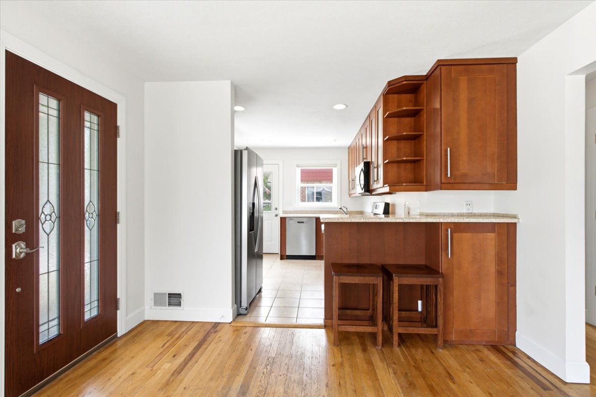 Hardwood flooring extends from the entry, complementing the wood cabinetry and light-toned countertops