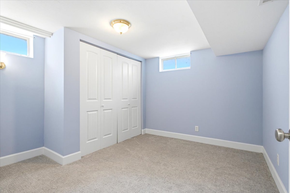 Interior room featuring light blue walls, light-colored carpet flooring, white baseboards, and two transom windows