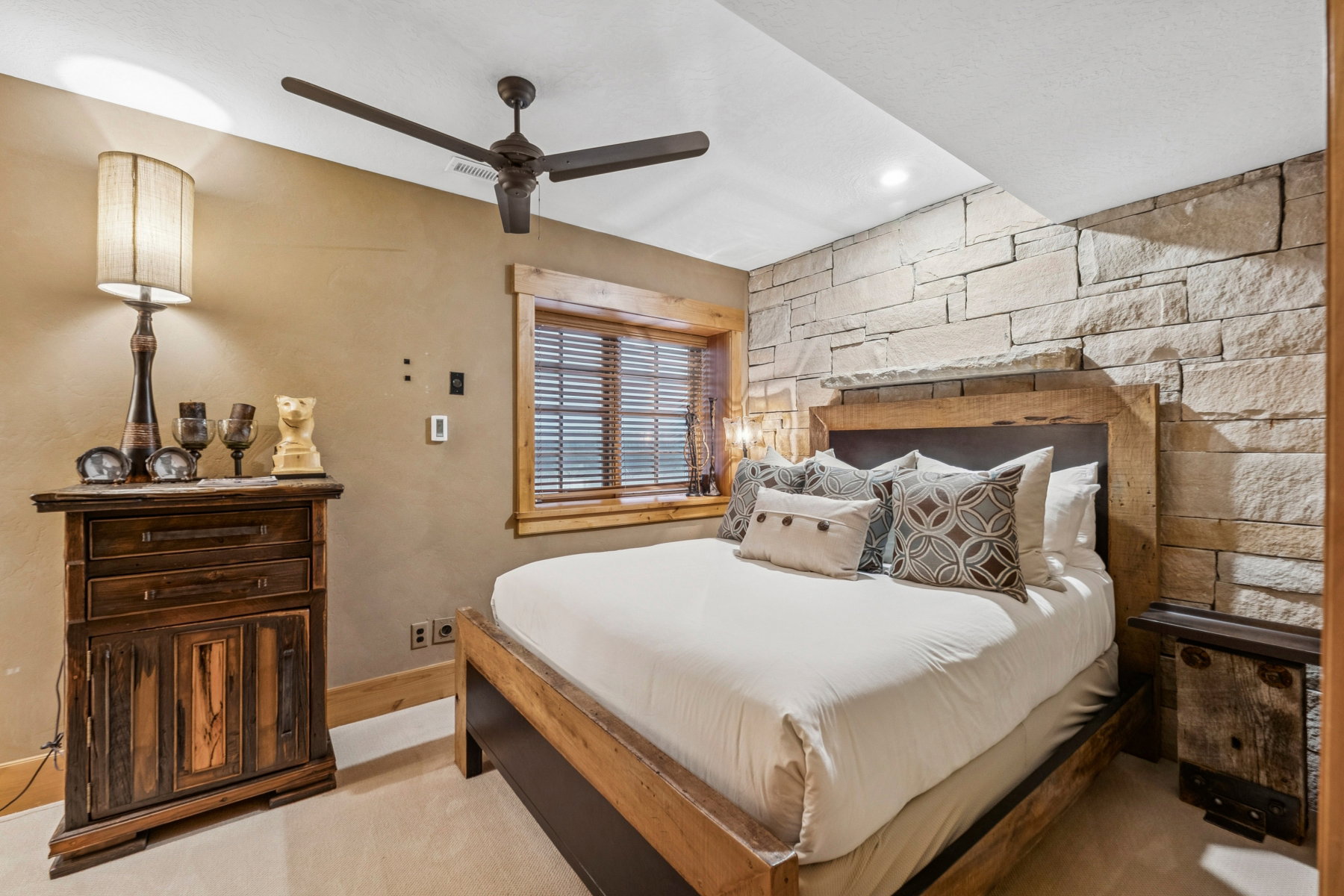 Bedroom featuring a natural stone accent wall, wood-finish window trim, a ceiling fan, recessed lighting, and carpet flooring