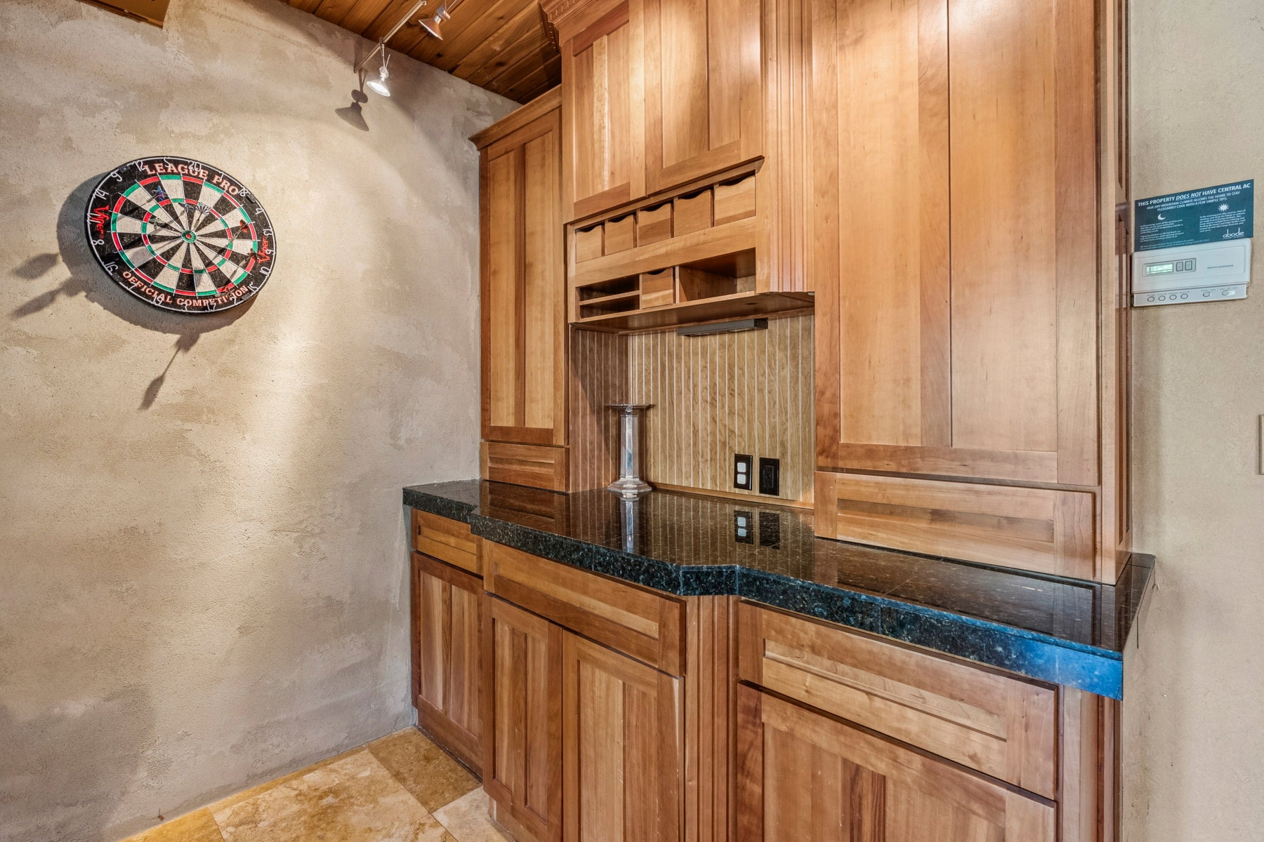 Built-in wood cabinetry with a dark stone-finish countertop, under-cabinet lighting, and a textured backsplash