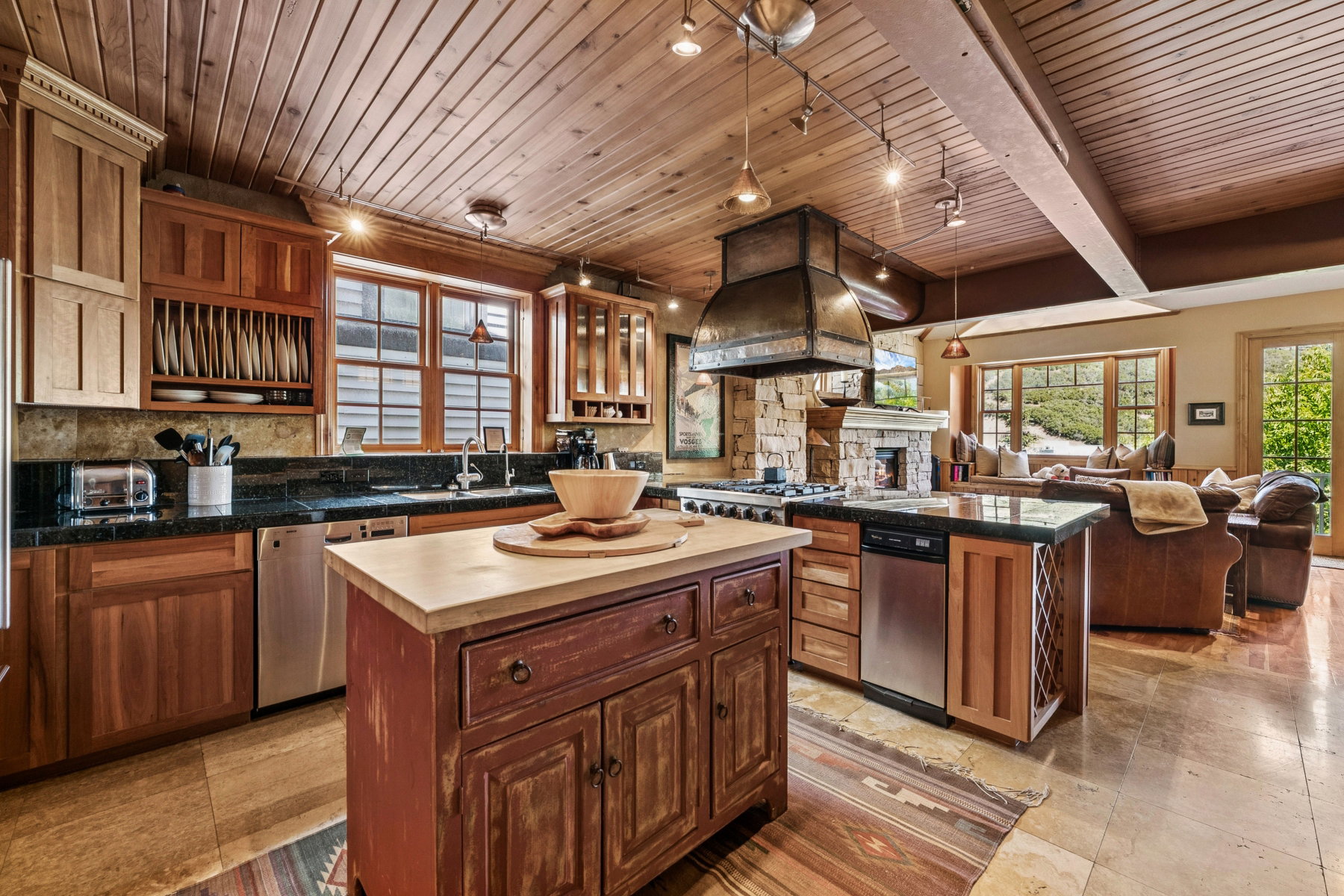 Kitchen featuring wood-paneled ceiling, wood cabinetry, stone backsplash, dark countertops, and stainless steel appliances