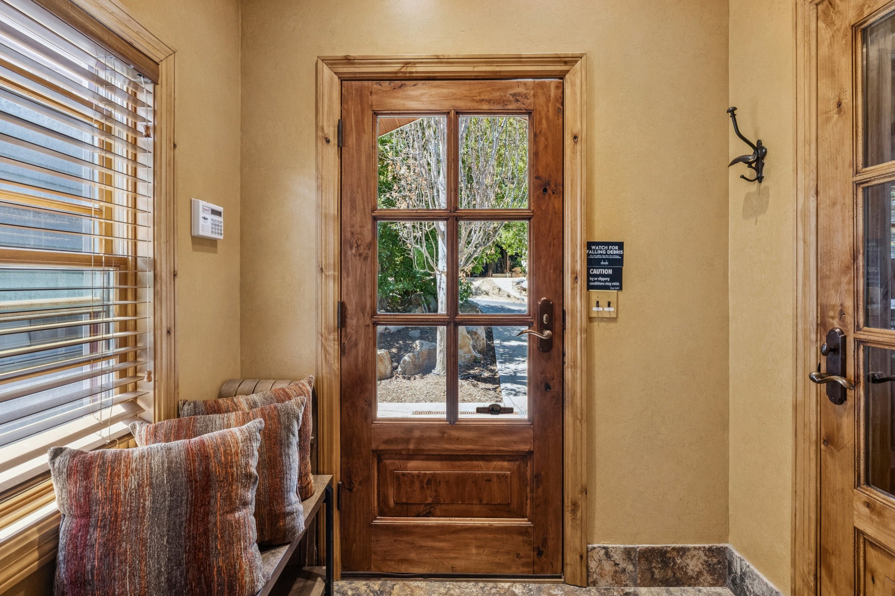Entryway featuring a wood-panel door with glass lites, wood-finish window blinds, and stone tile flooring