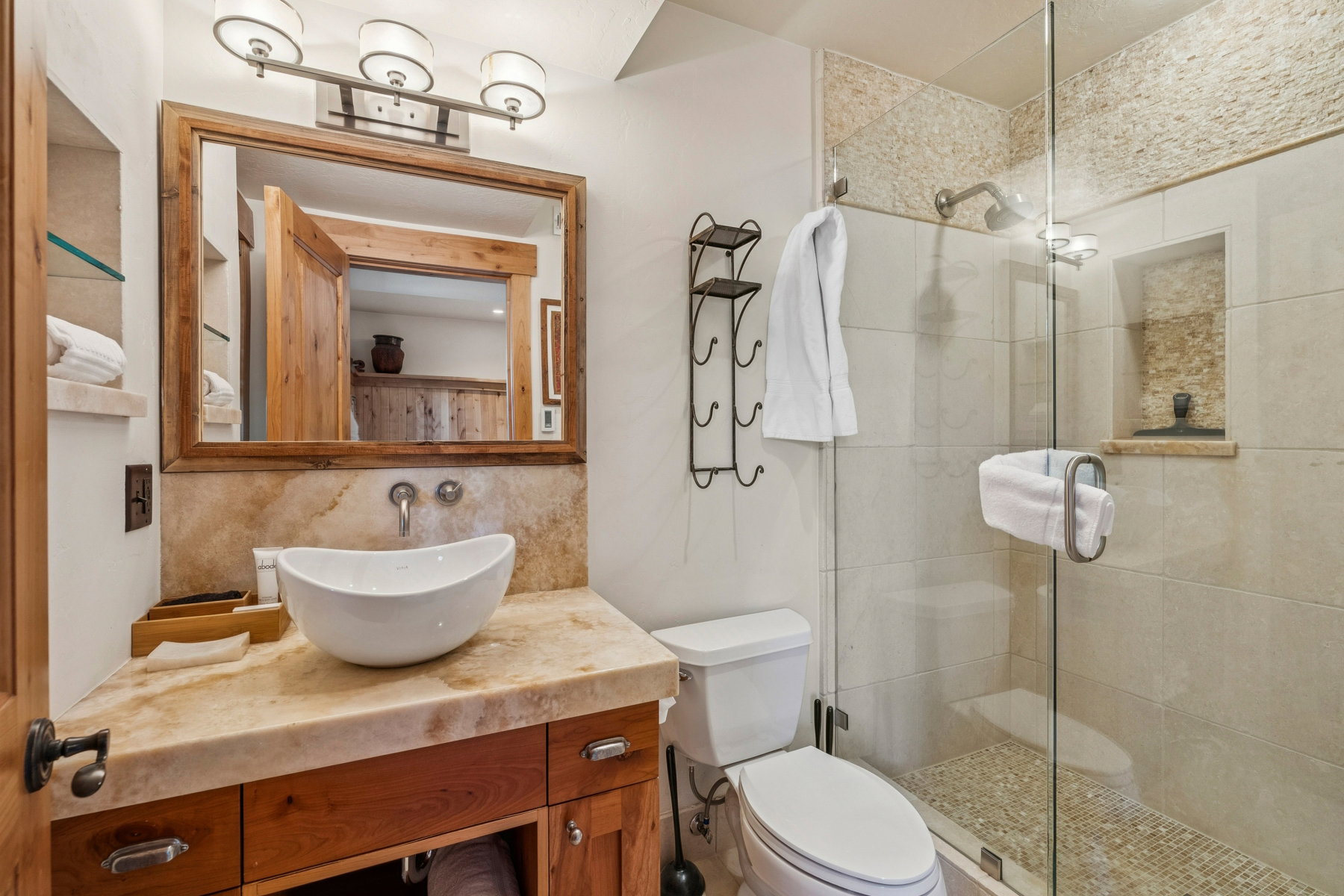 Natural stone vanity with an oval vessel sink and wall-mounted faucet