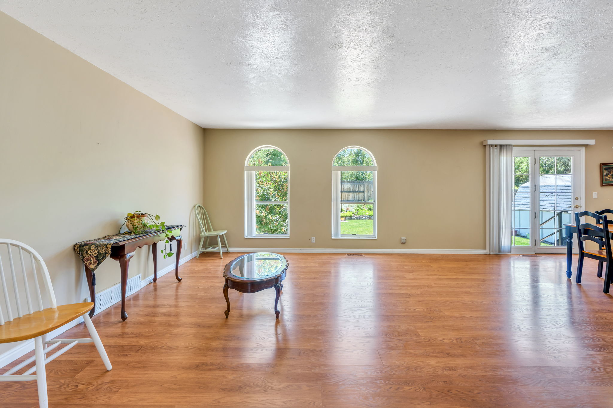 Spacious open-concept room featuring wood-finish flooring, neutral wall tones, and two arched windows
