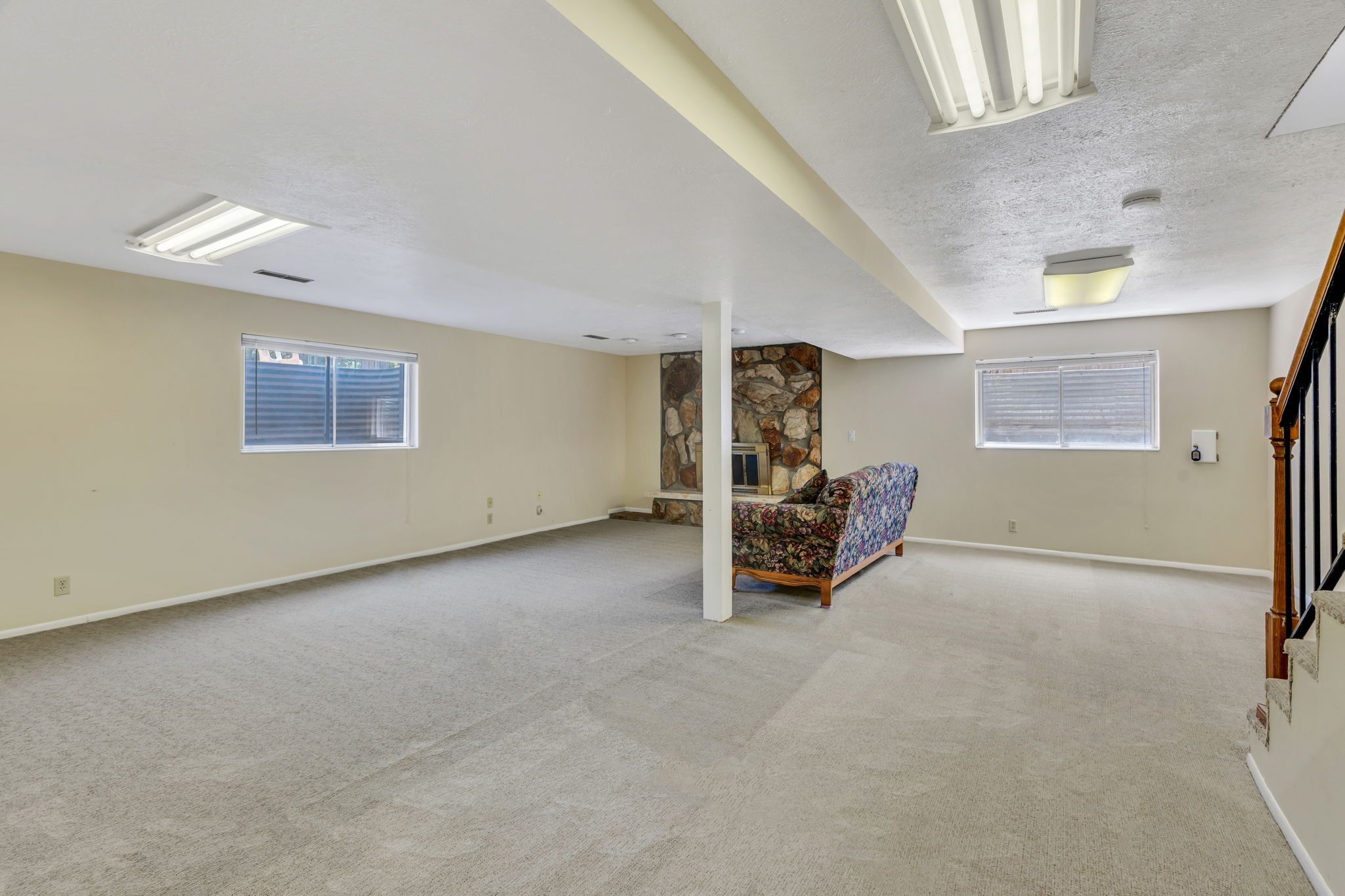 Spacious finished lower level featuring light-toned carpeting, a built-in stone fireplace, two egress windows, and recessed lighting