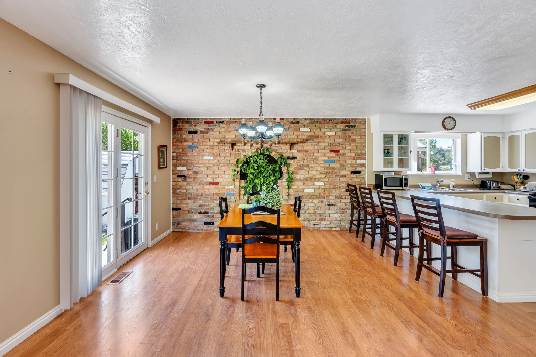 Open concept dining area featuring wood-finish flooring and a brick accent wall with an arched niche