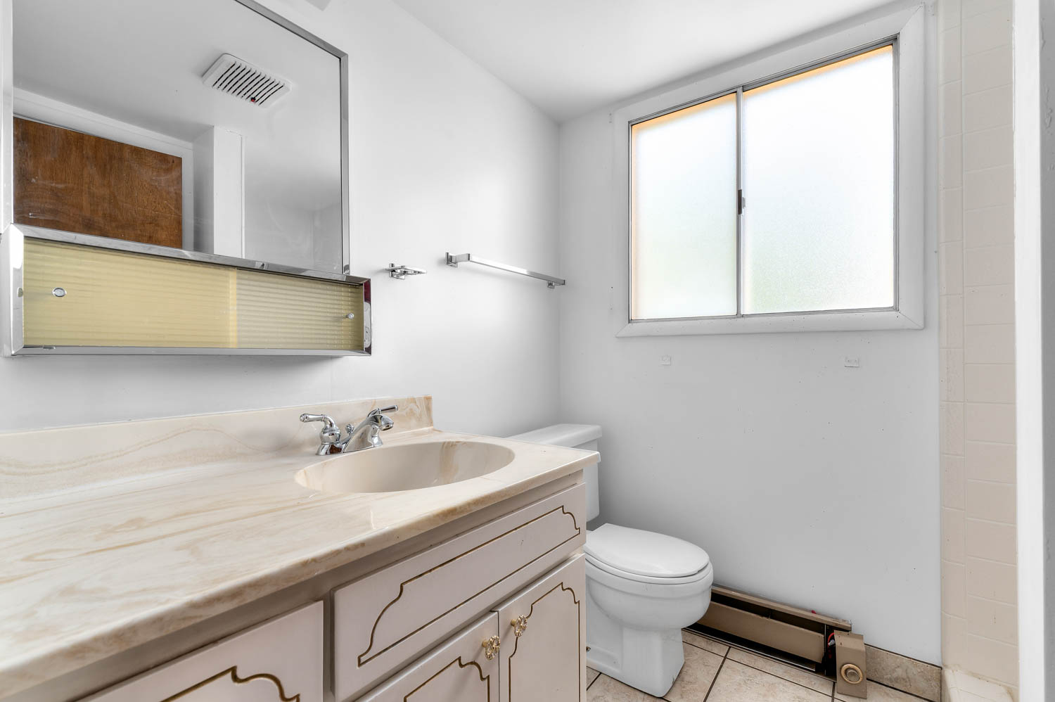 Bathroom featuring a single vanity with an integrated sink, patterned countertop, and decorative cabinet doors