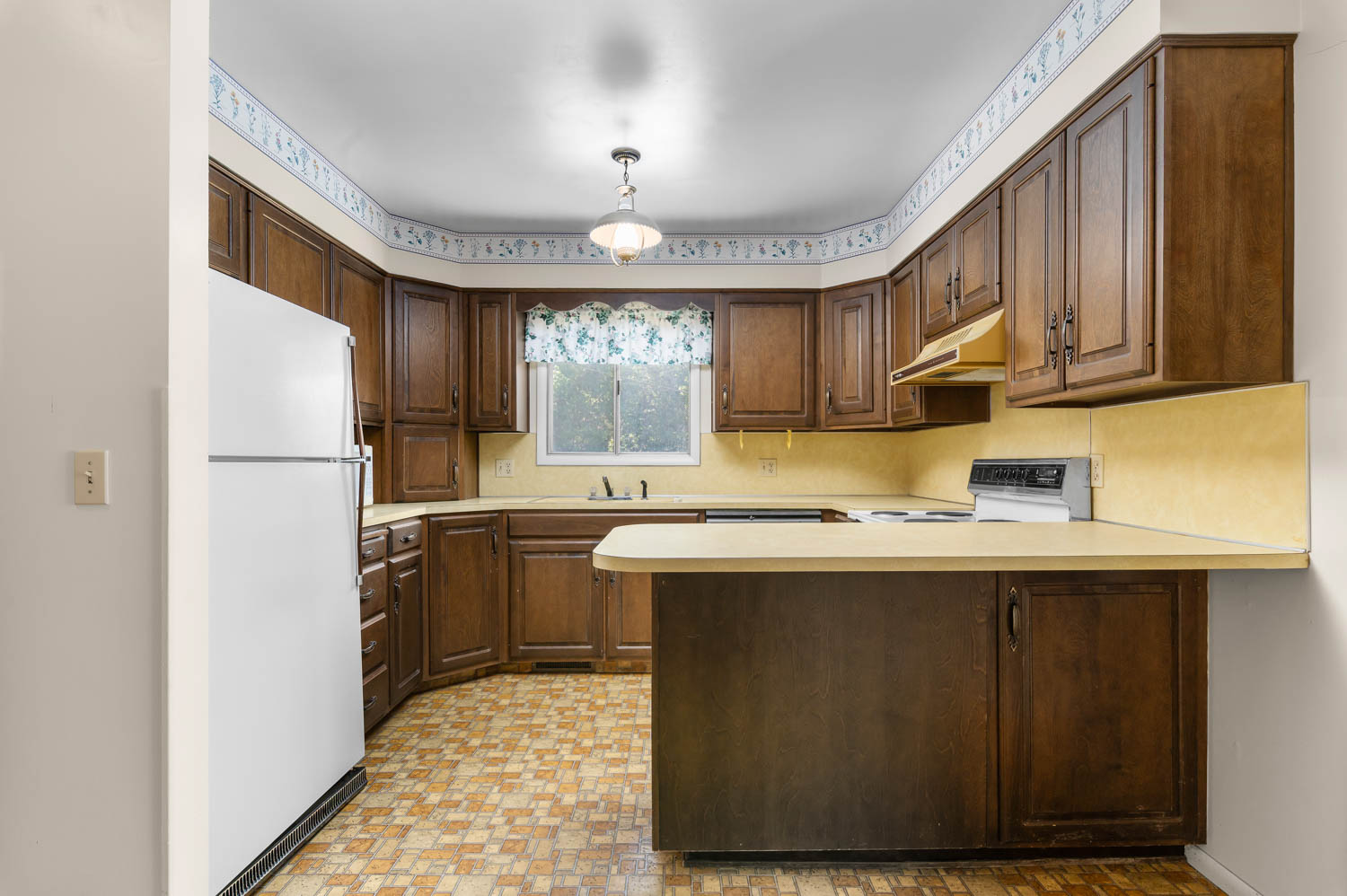 Kitchen featuring wood-finish cabinetry, light-toned countertops, and a built-in cooktop