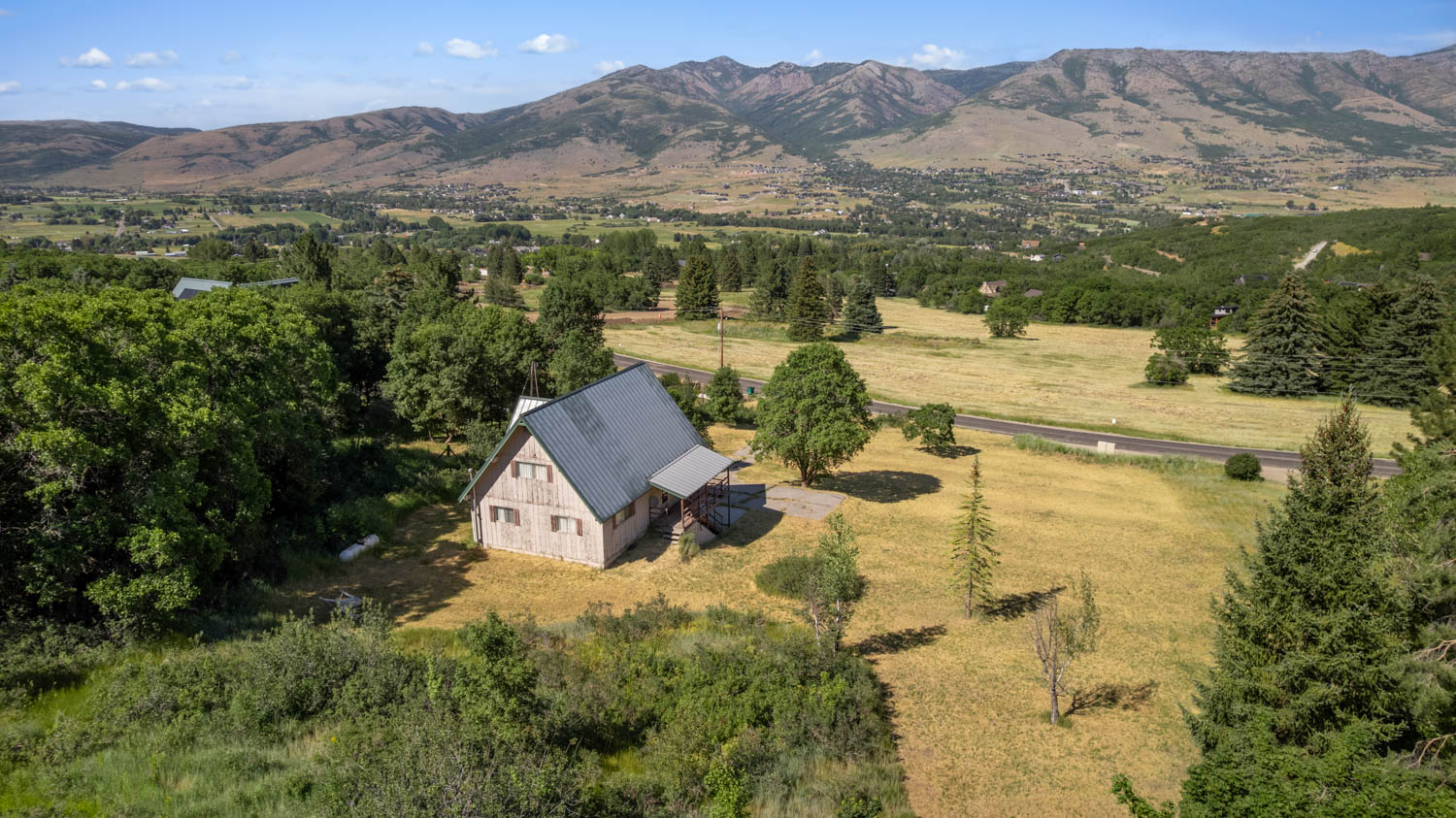 A-frame style residence with a metal roof, featuring a light-toned exterior and a covered entry