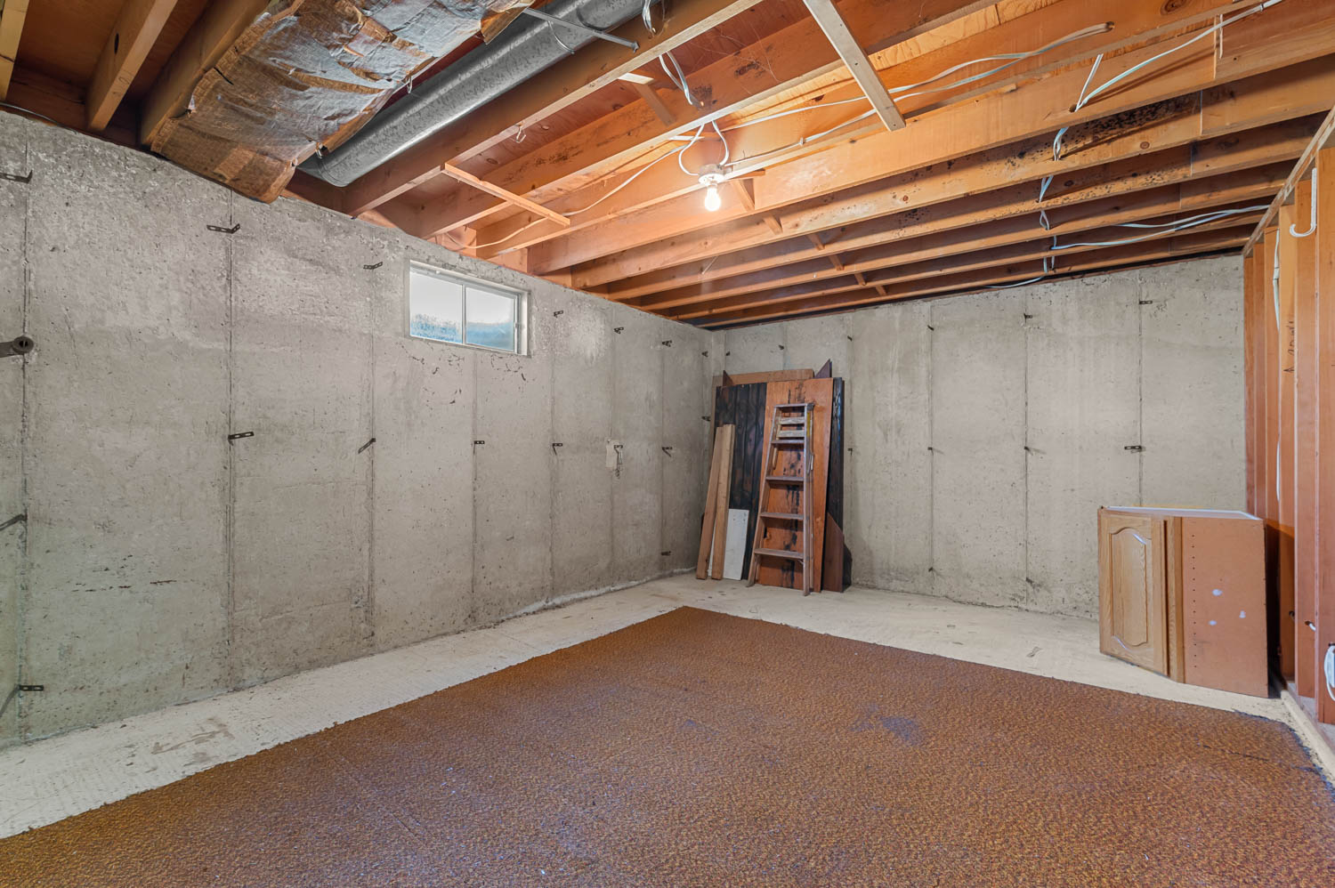 Unfinished basement featuring concrete walls and exposed wood ceiling joists