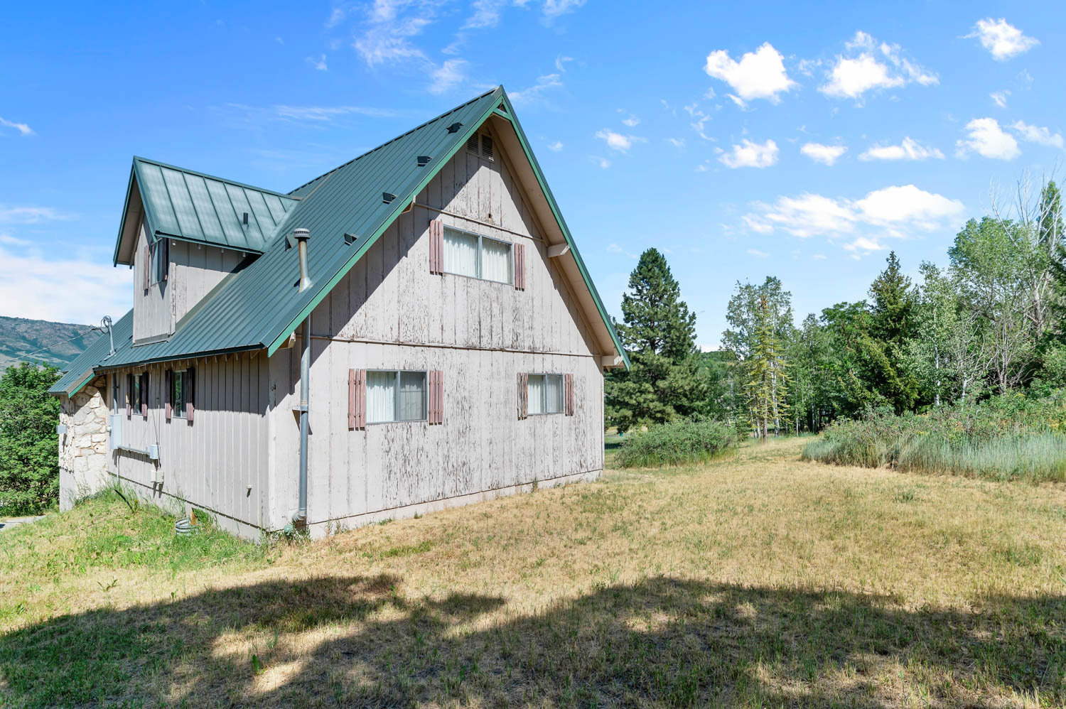 Gabled wood-sided exterior with a standing seam metal roof and stone accents