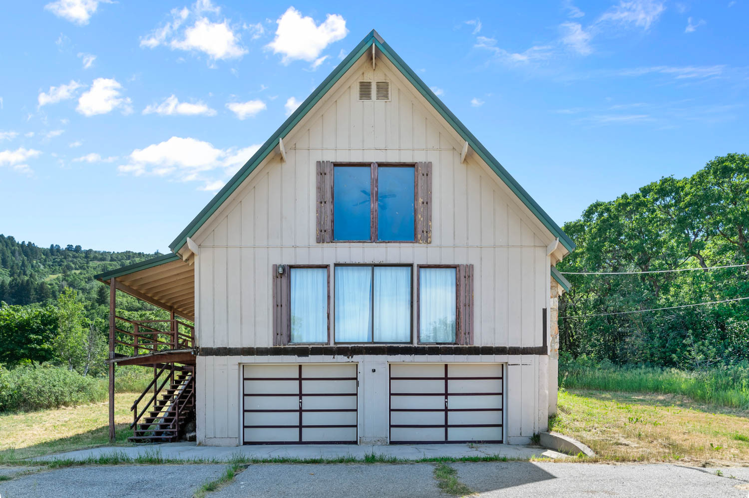 Gable-roofed structure featuring board and batten siding and a covered balcony with exterior staircase