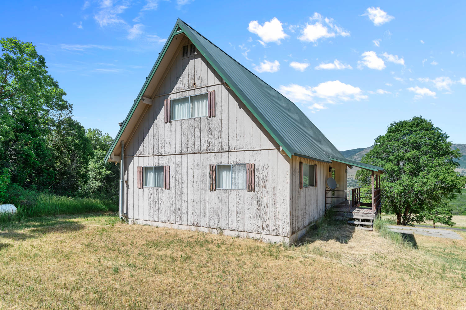 A-frame style residence featuring a green metal roof and light-toned vertical siding