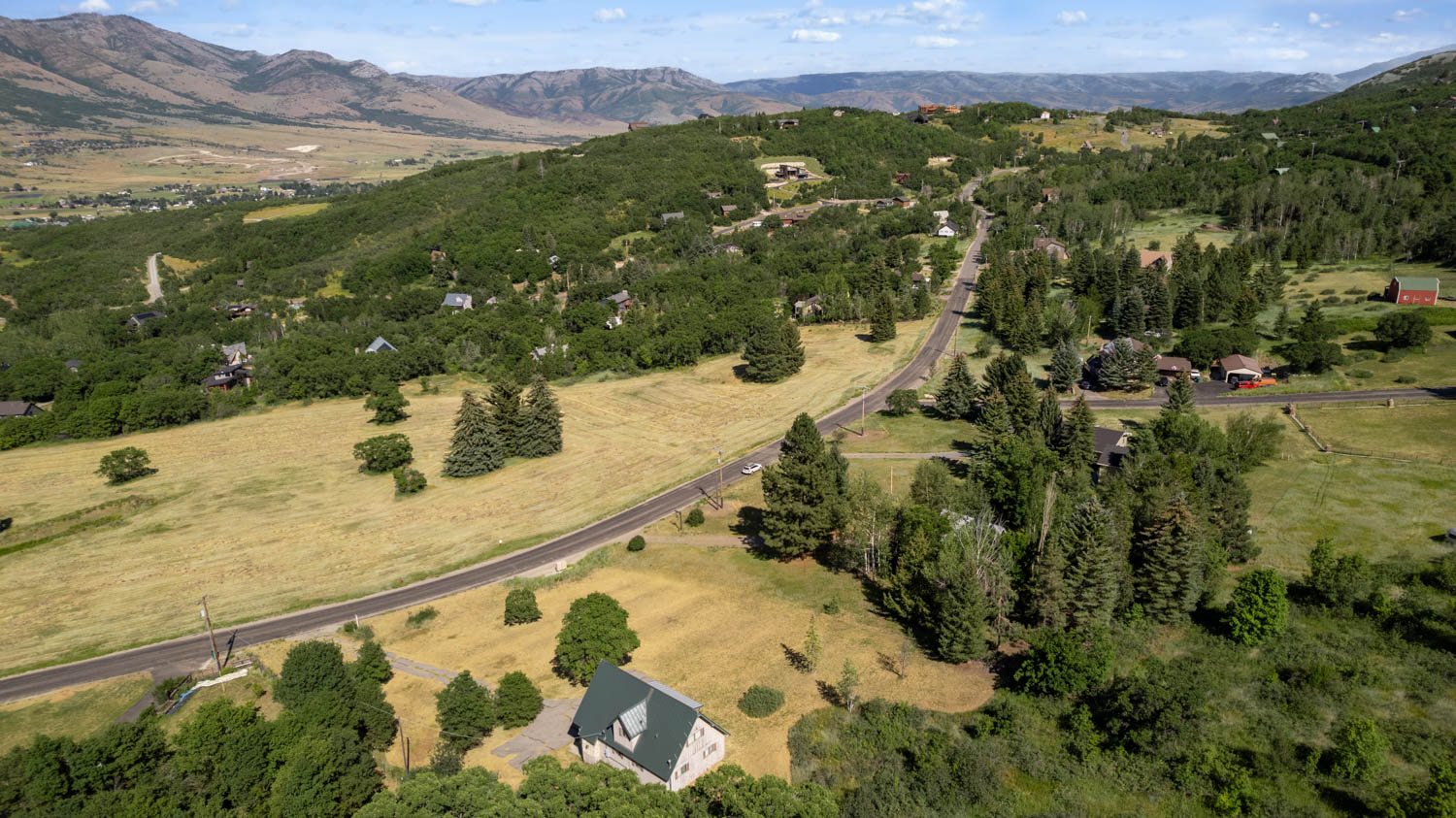 Mountainous landscape featuring a winding road traversing green hills and valleys