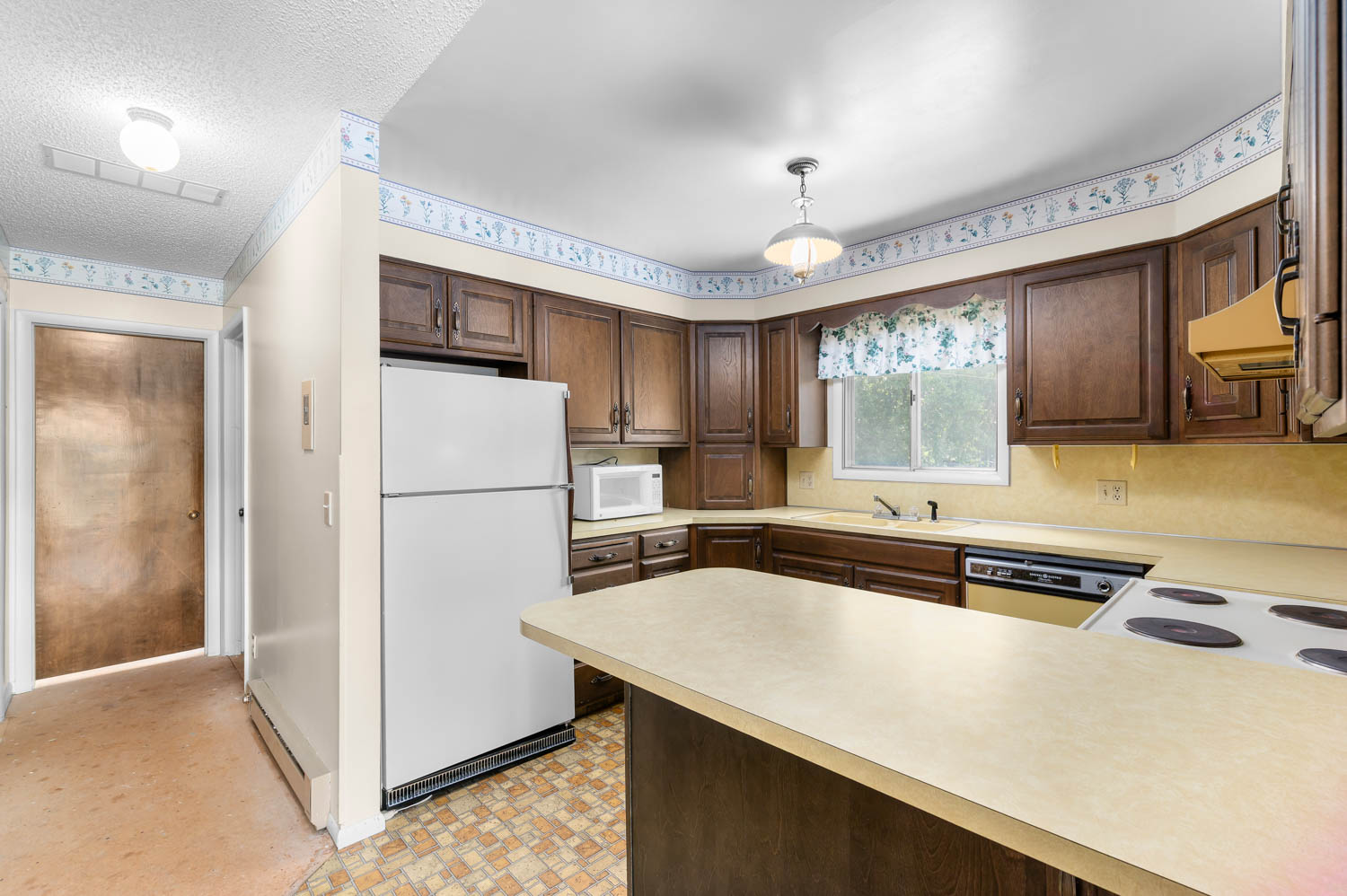 Kitchen area featuring wood cabinetry, laminate countertops, a built-in electric range, and a double basin sink