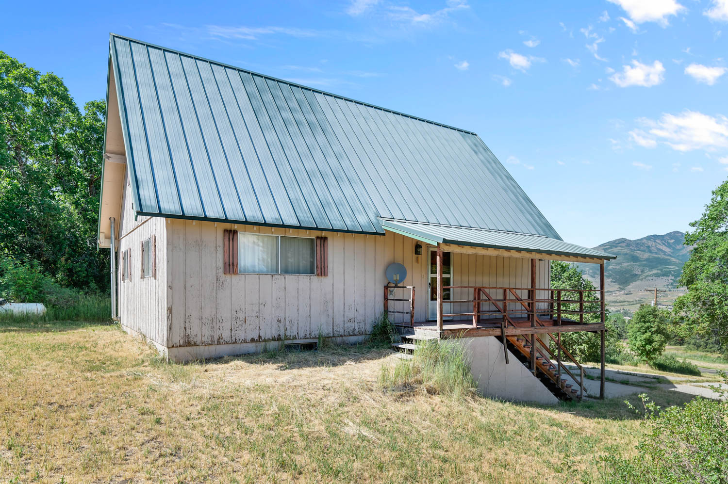 A-frame style residence featuring a metal roof, extended front porch with wood railings, and a walk-out basement