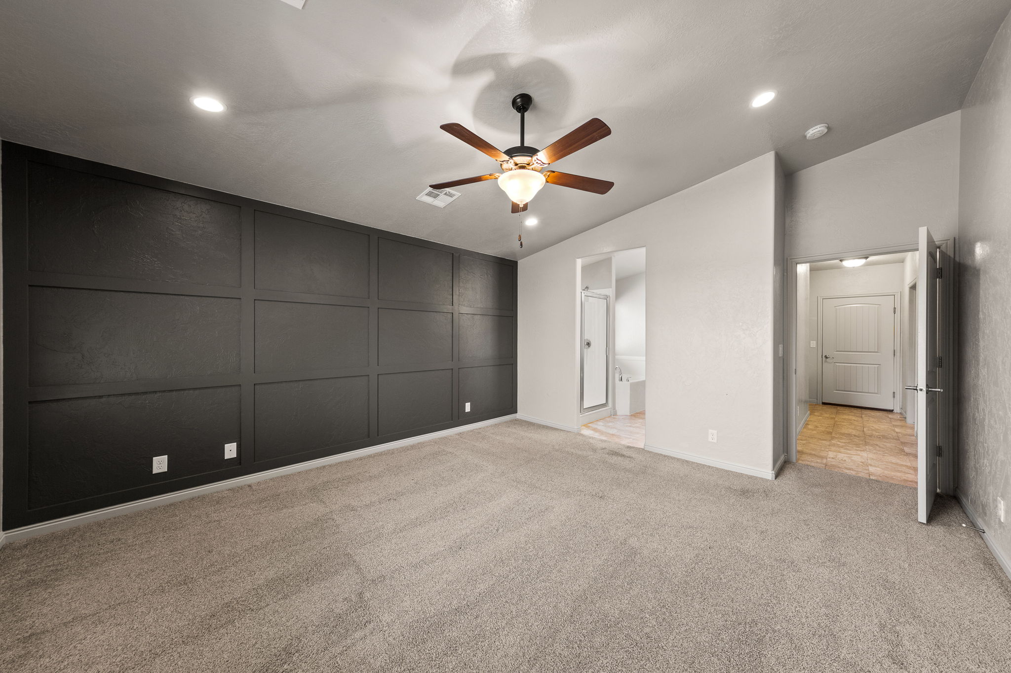 Room featuring a dark paneled accent wall, neutral carpeting, and recessed lighting