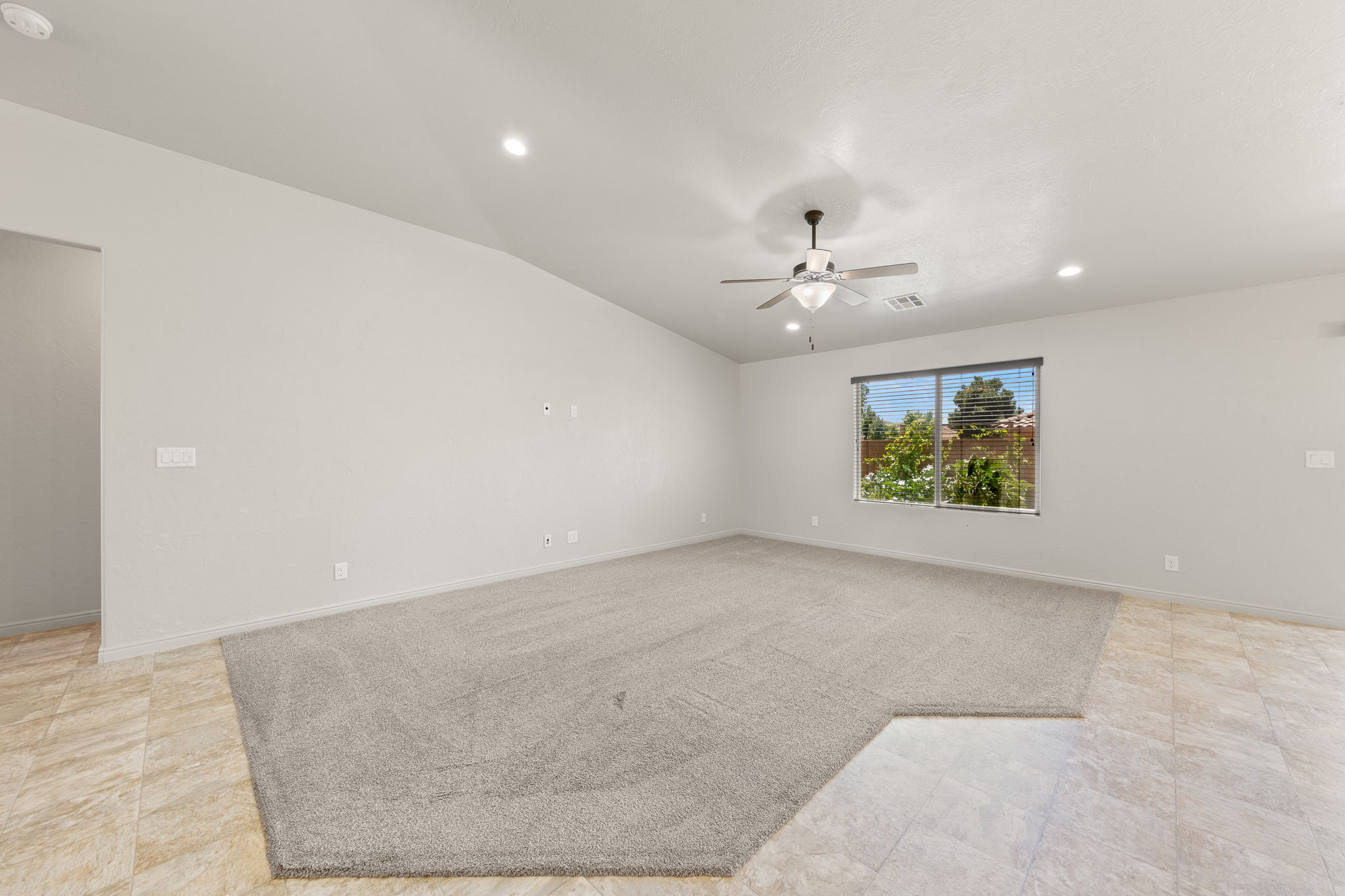 Spacious room featuring light-toned carpeting and perimeter tile flooring
