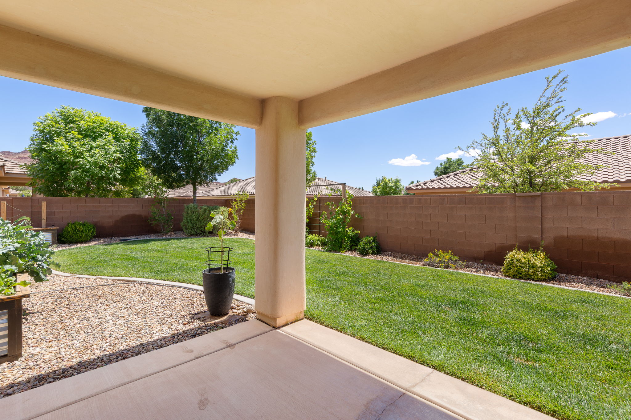 Covered patio with concrete flooring, overlooking a gravel and lawn area
