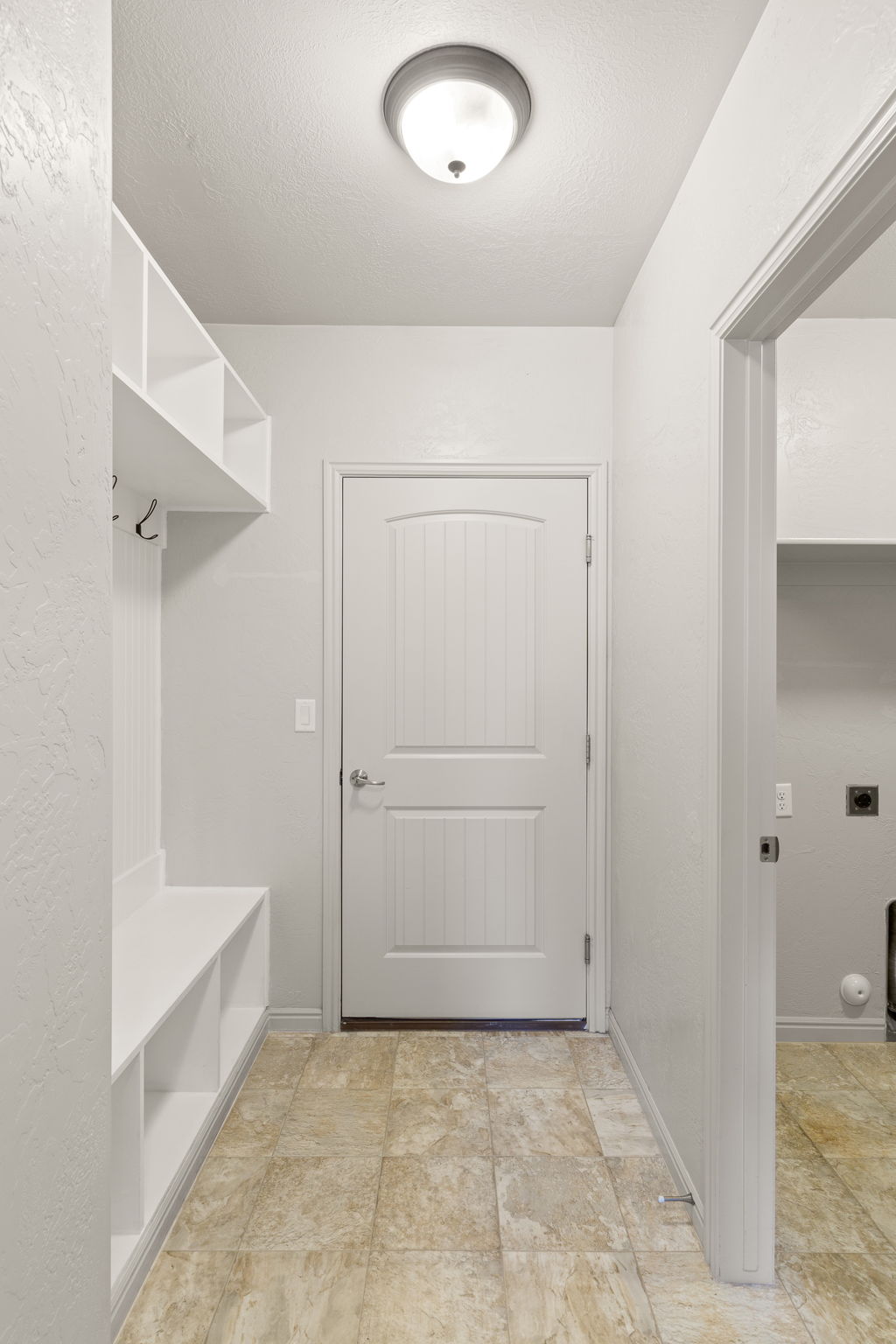 Entryway featuring built-in shelving, integrated coat hooks, a built-in bench, and durable tile flooring