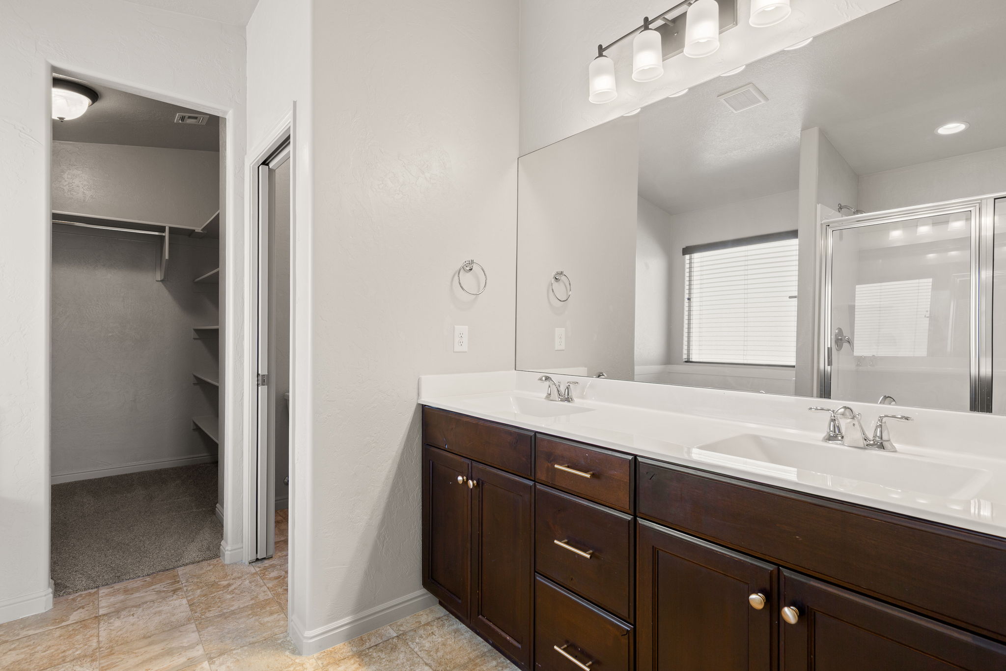 Bathroom featuring a dual vanity with dark wood cabinetry, white countertops, and a large wall-mounted mirror