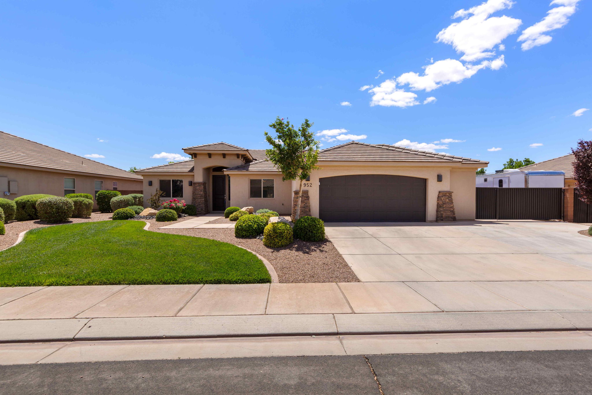 Contemporary stucco exterior with a stone-clad entry, two-car garage, and concrete driveway
