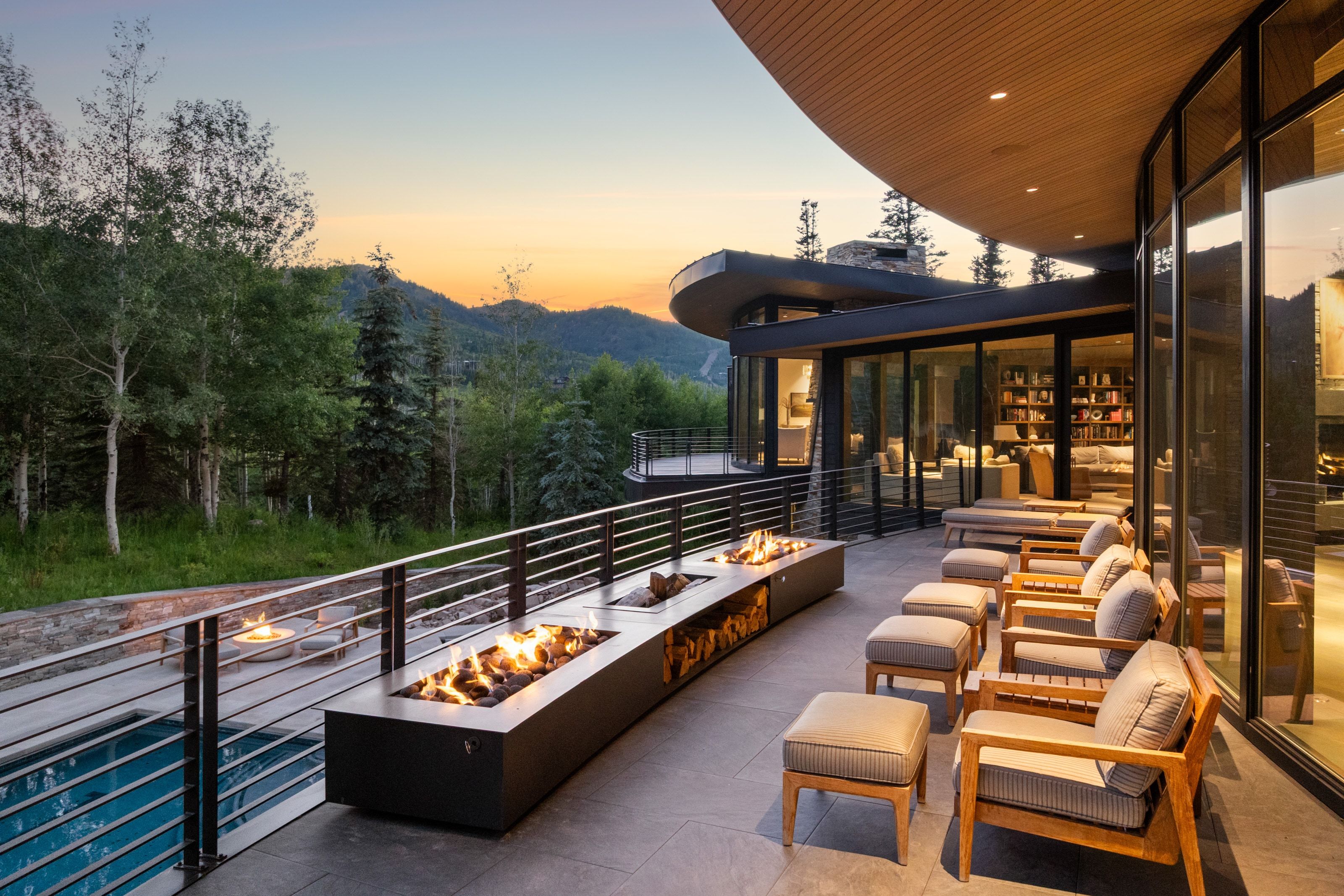 Expansive curved patio featuring a linear fire pit, tile flooring, and glass railing