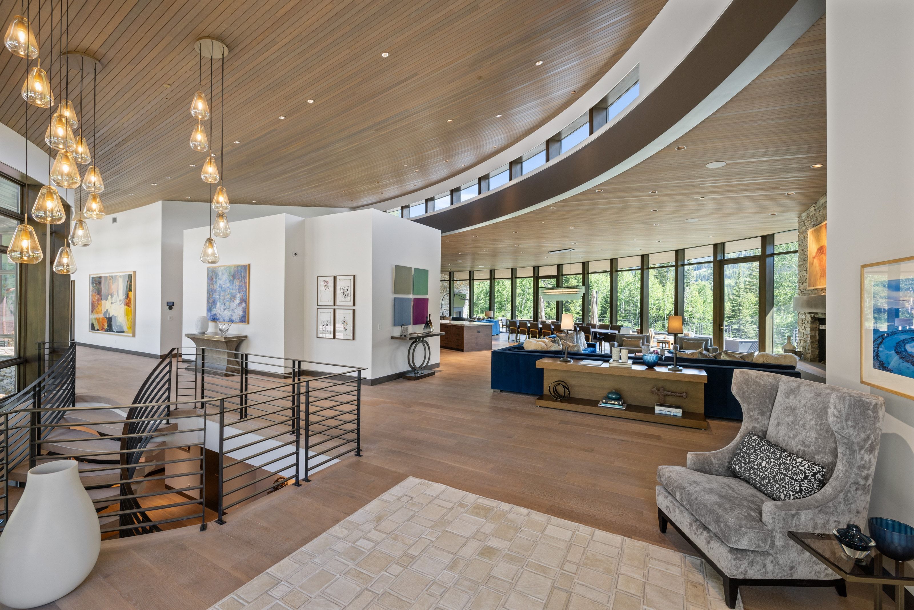 Open concept interior featuring wood-finish flooring, a curved wood-panel ceiling, and extensive floor-to-ceiling windows