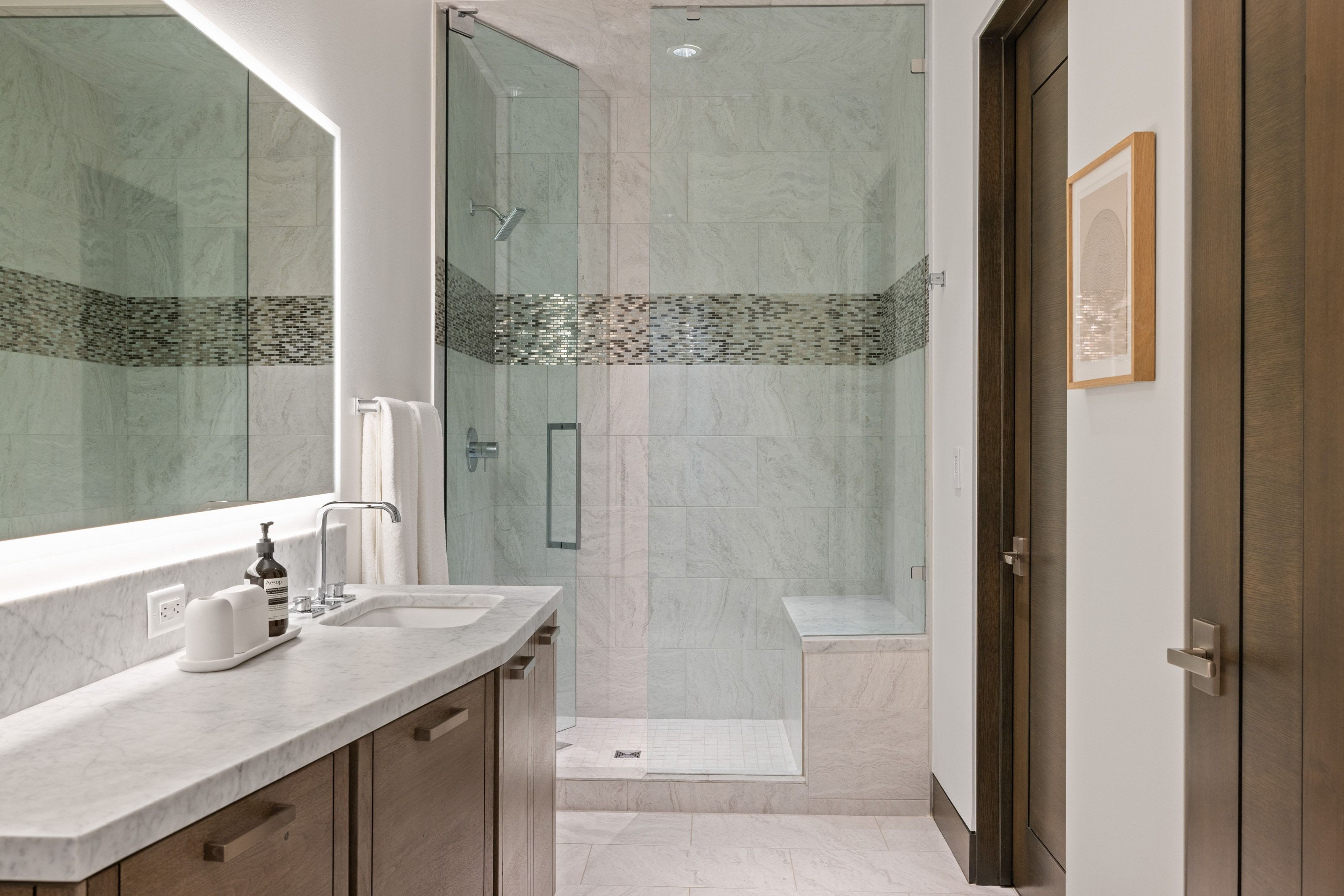 Bathroom featuring a shower with glass enclosure, built-in bench, and accent tile band