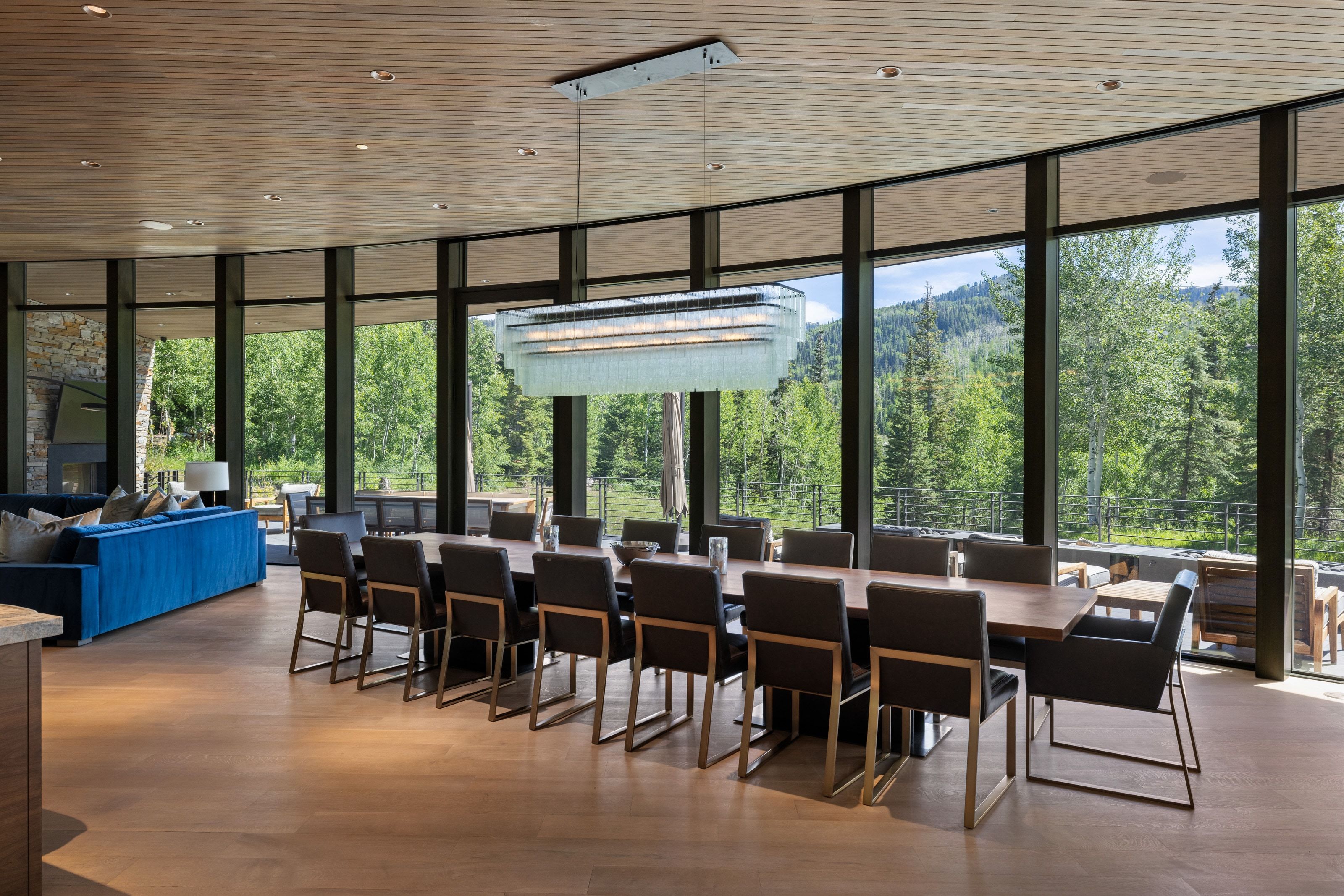 Open-concept dining area featuring expansive floor-to-ceiling windows, wood-finish flooring, and a slat wood ceiling