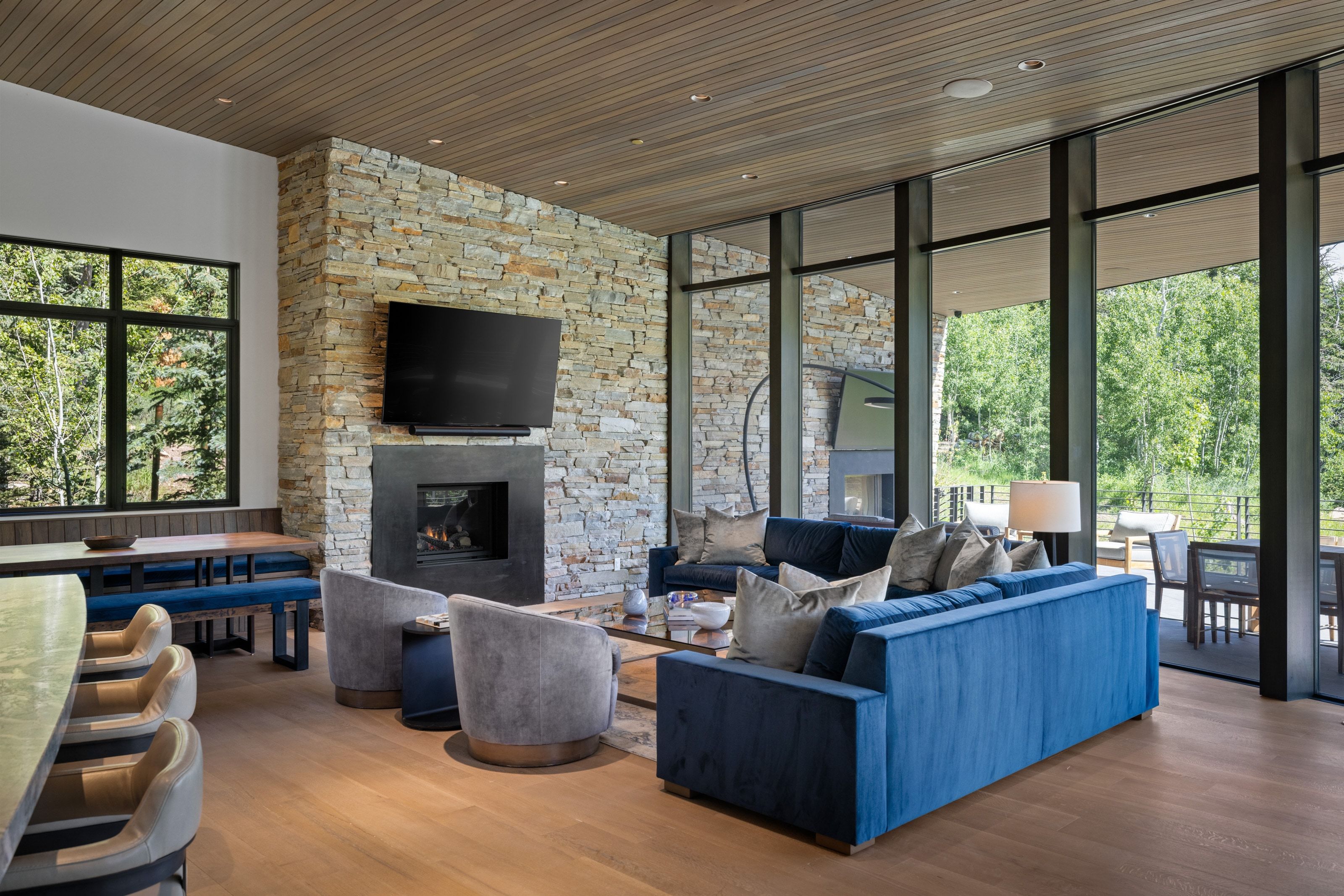 Expansive living area featuring a full-height stone fireplace with a built-in hearth, wood-finish flooring, and a wood-paneled ceiling