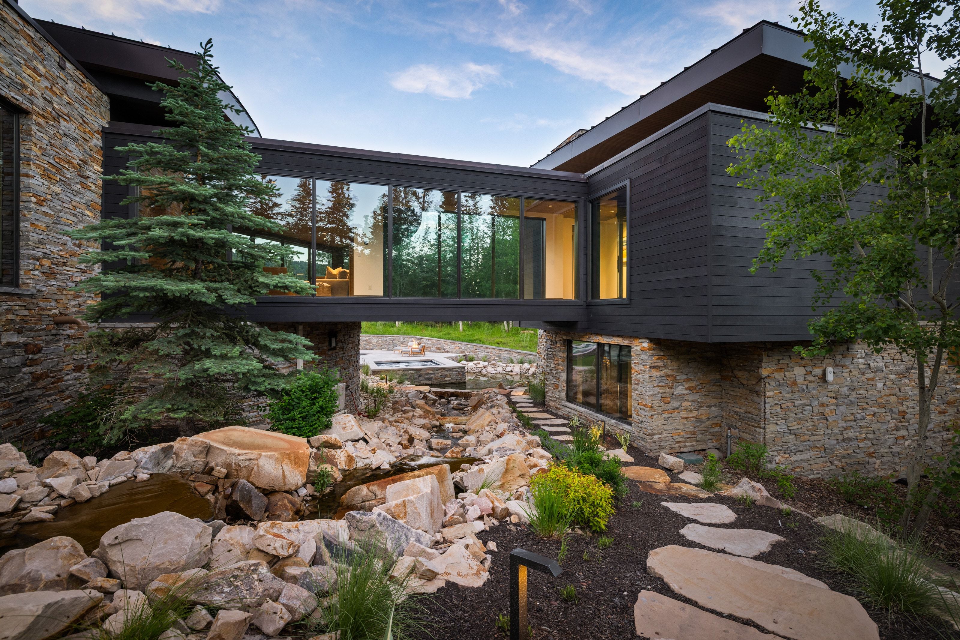 Contemporary exterior featuring stone and dark siding with a glass-enclosed skybridge