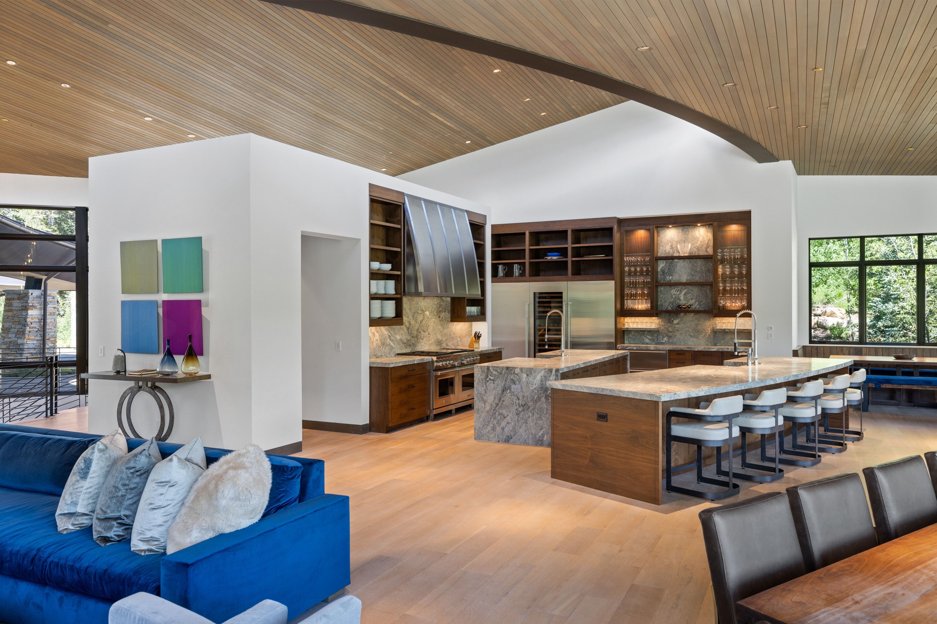 Spacious open-concept living area featuring a kitchen with dual stone-topped islands, integrated stainless steel appliances, and wood cabinetry