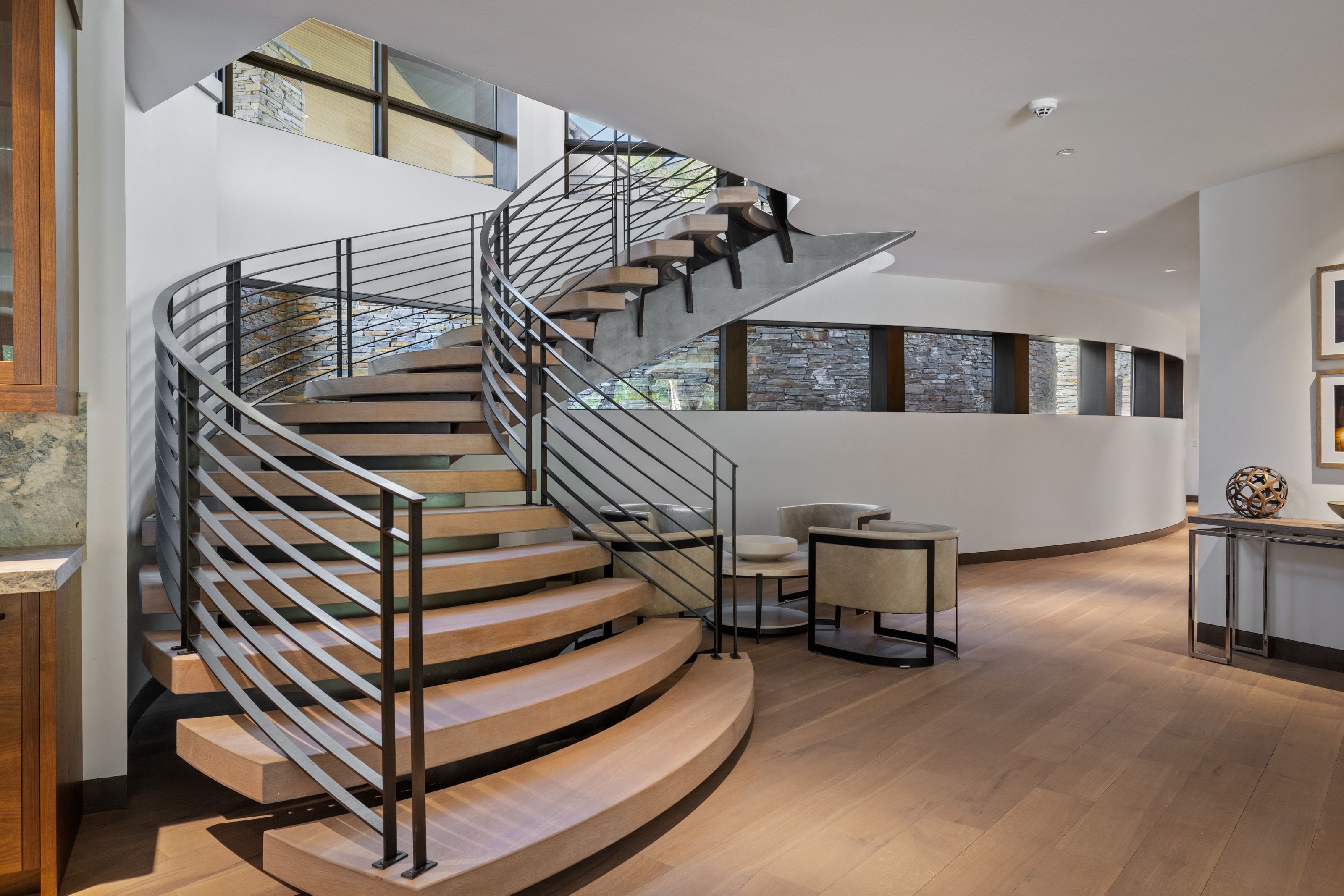 Curved floating staircase with wood-finish treads and contemporary metal railings