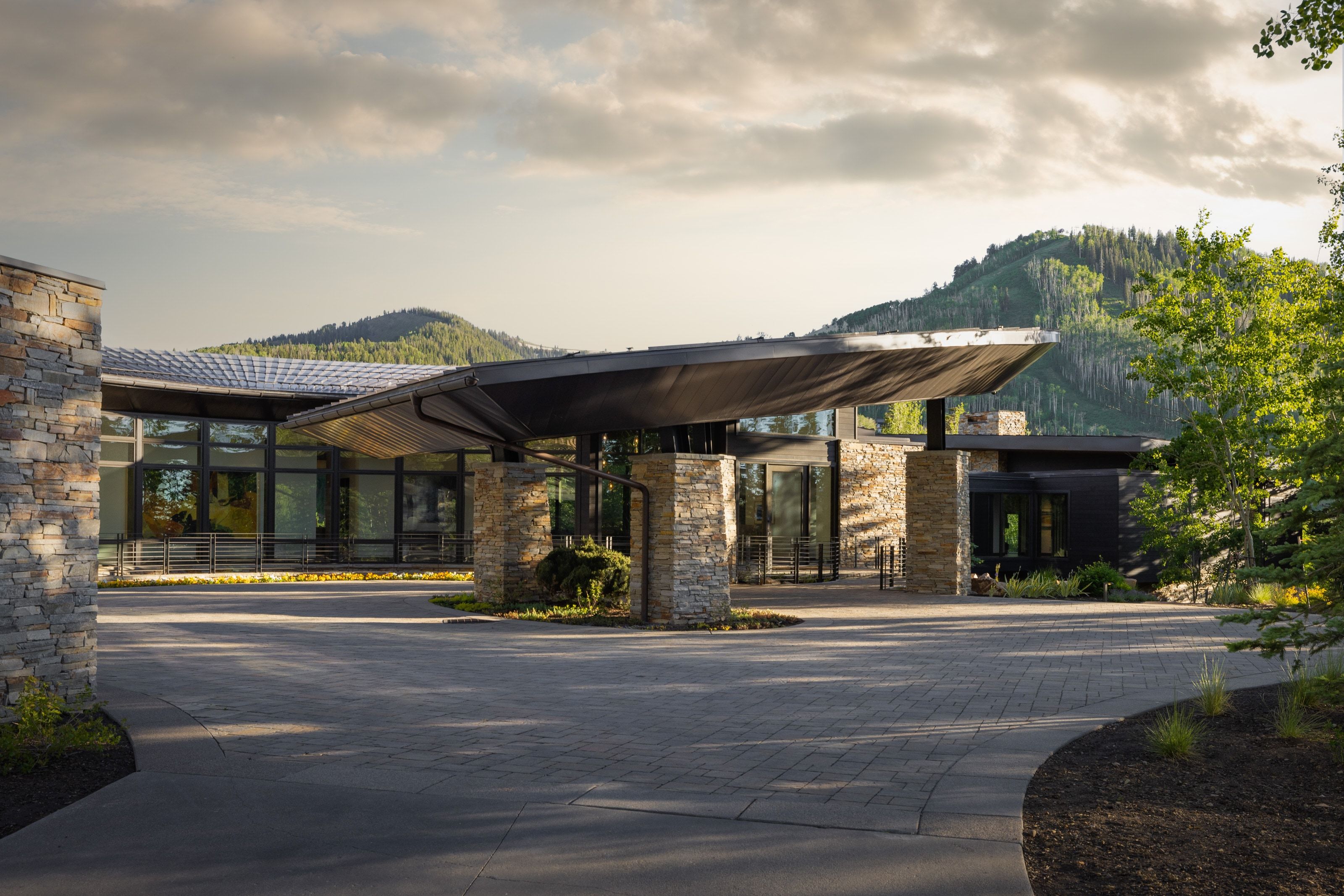 Contemporary stone and glass exterior with a distinctive porte-cochère
