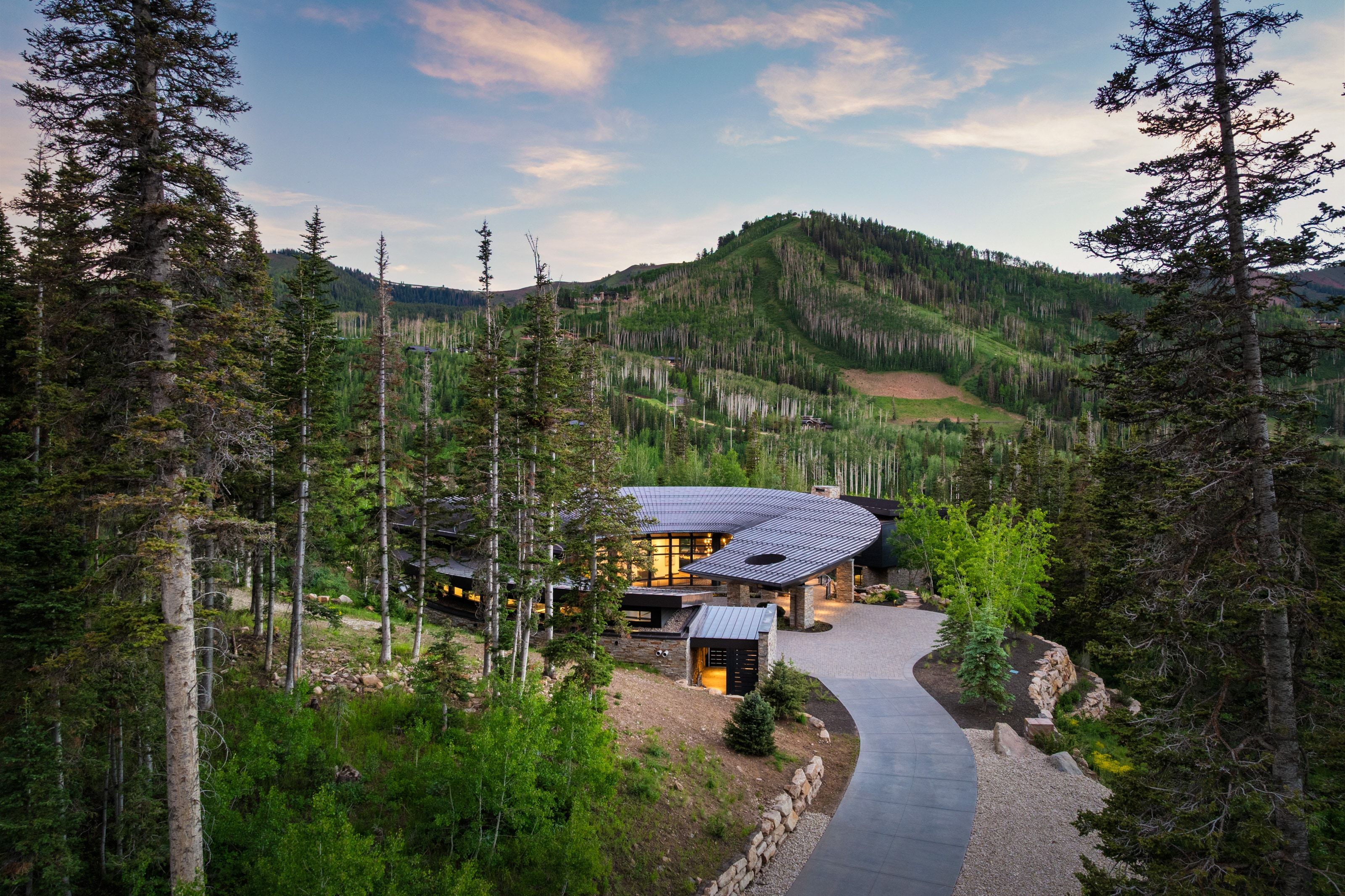 Curved architectural residence featuring extensive glazing and a dark-toned roof structure