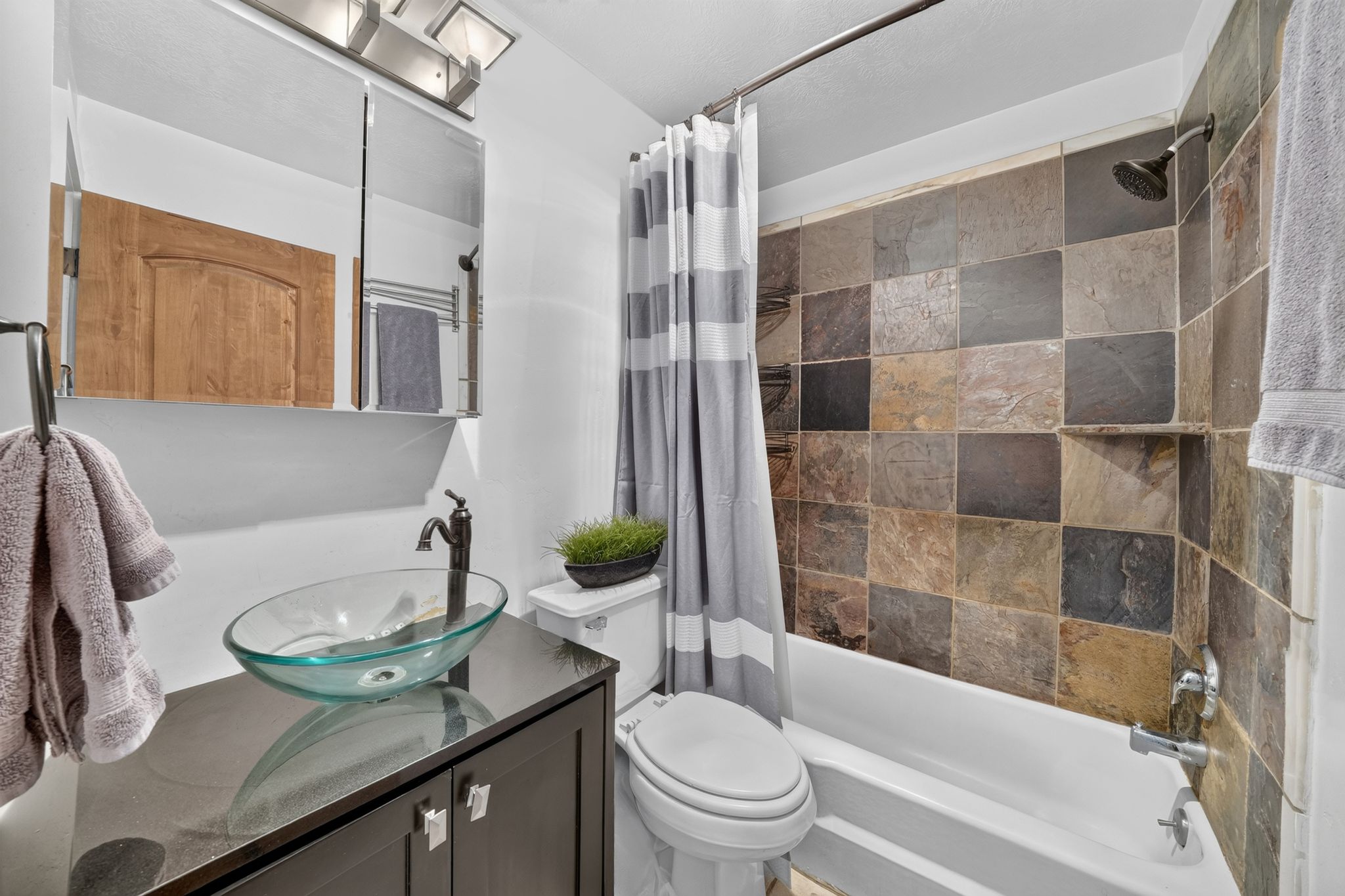 Bathroom with a slate-tiled tub and shower surround, featuring a built-in shower niche