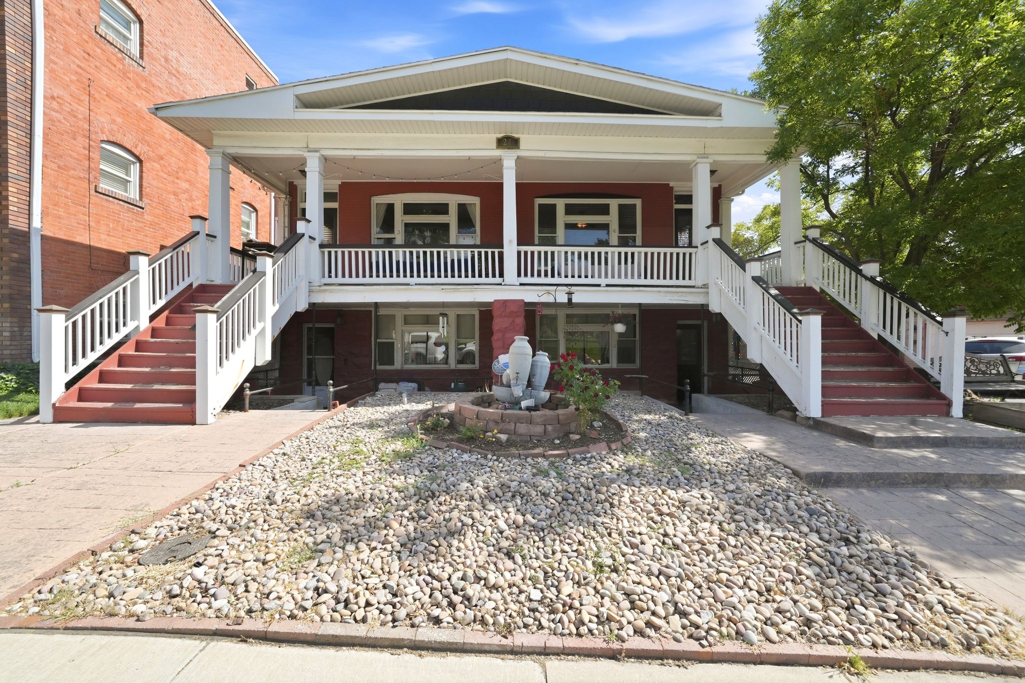 Two-story facade with a prominent upper-level porch featuring white railings and columns