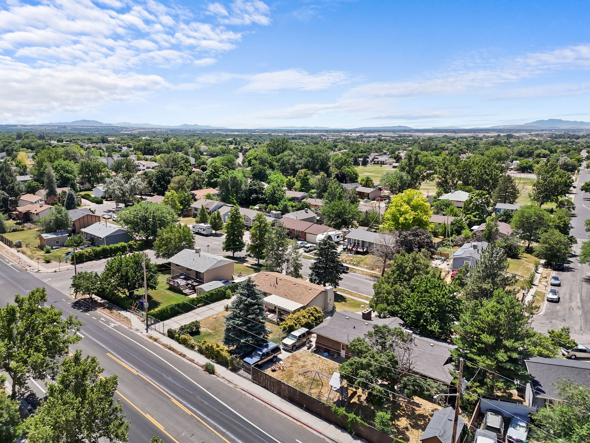 Residential neighborhood featuring mature trees and mountain scenery
