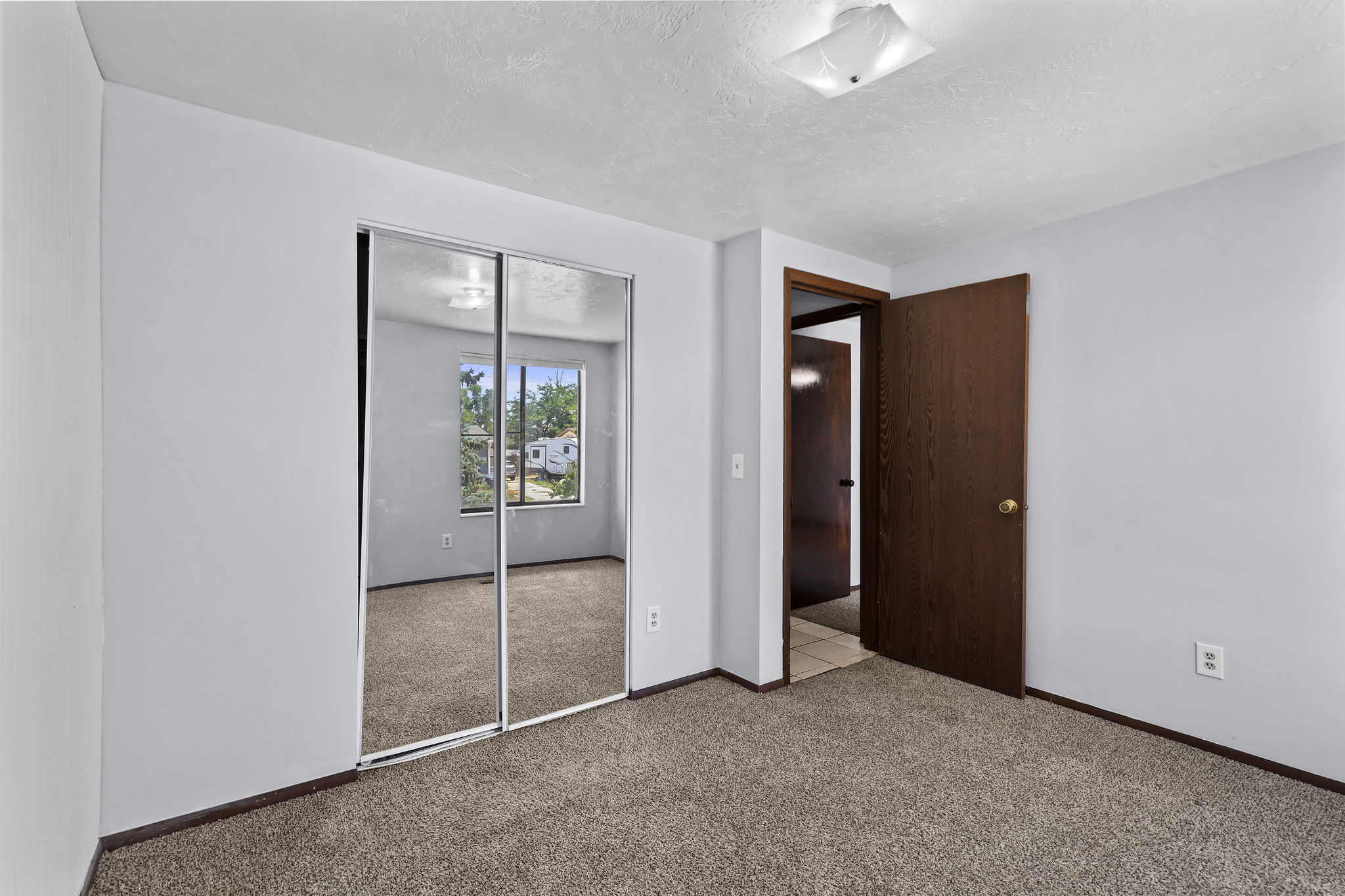 Room featuring light gray walls, brown carpet flooring, and a flat white ceiling