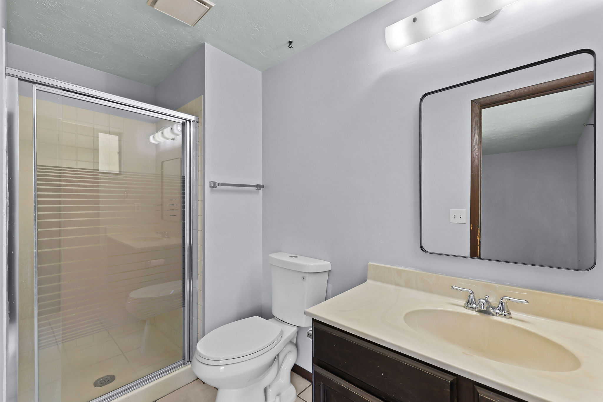 Bathroom vanity with a cream-toned countertop, undermount sink, and chrome faucet