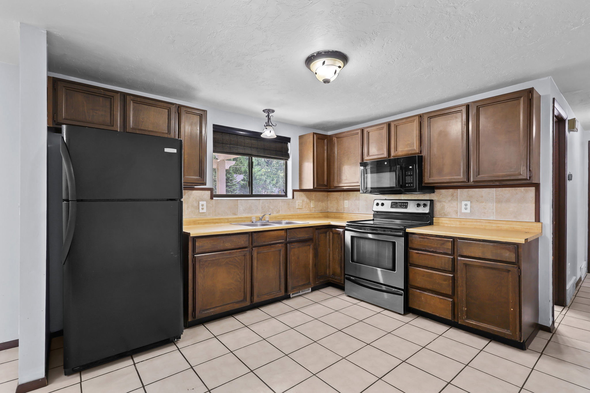 Kitchen featuring dark wood cabinetry, light-toned countertops, and a neutral tile backsplash