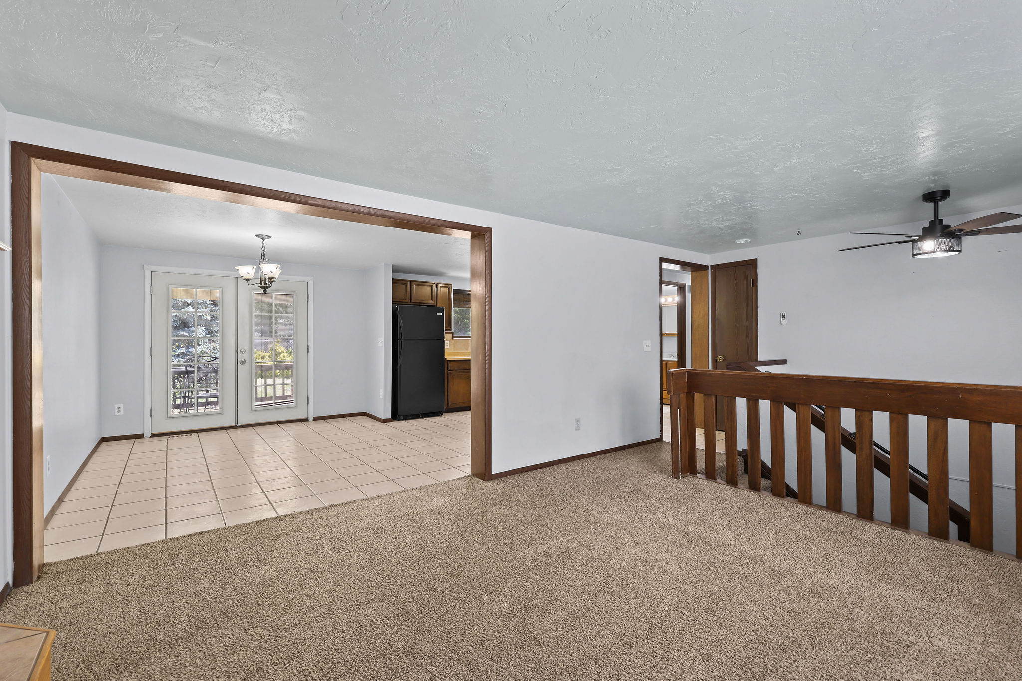 Expansive common area featuring carpet flooring and a wood-finish staircase with matching railing