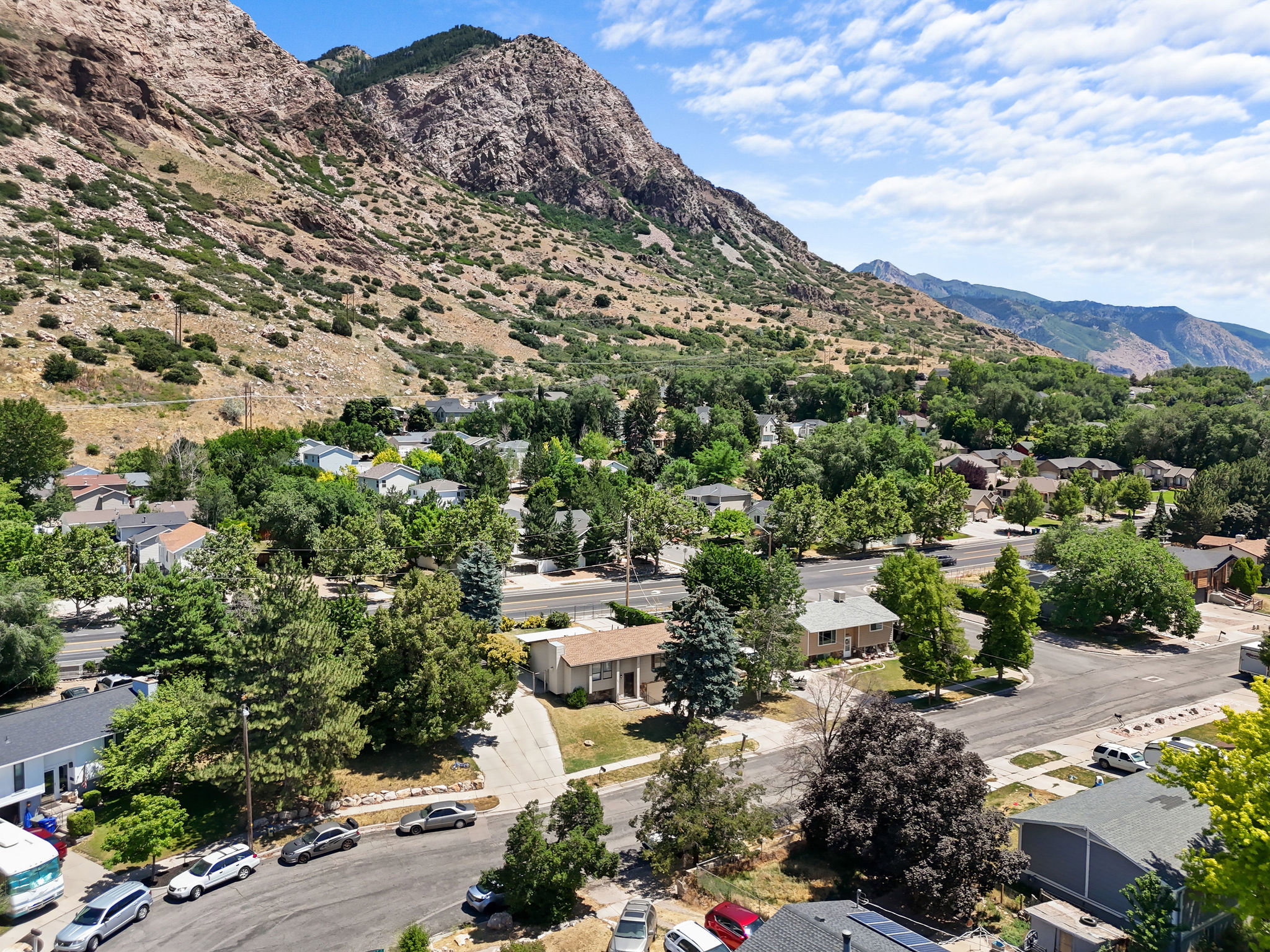 Residential neighborhood featuring mature trees and mountain scenery