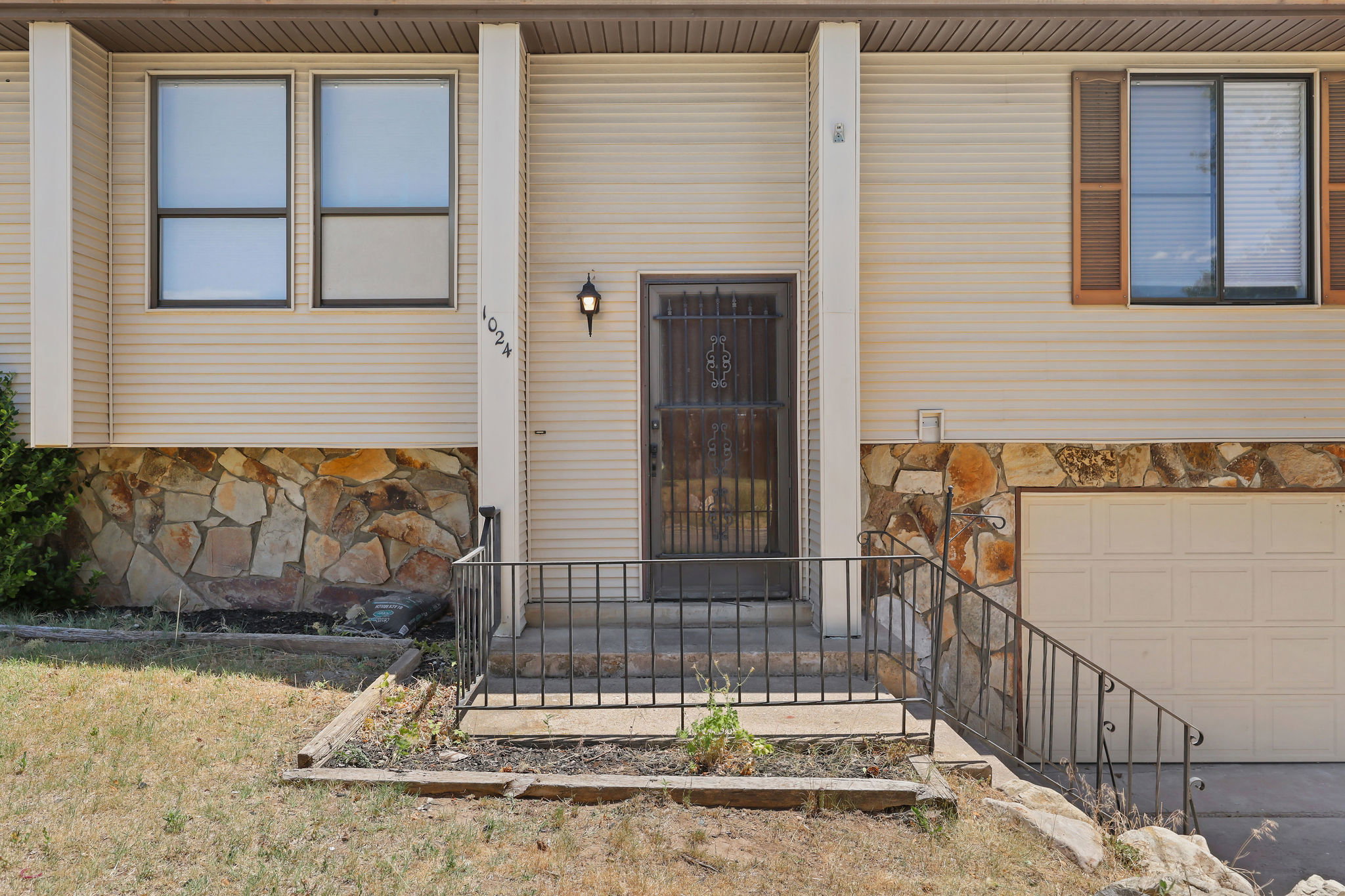 Split-level exterior featuring light-colored siding, a stone facade, and an integrated garage