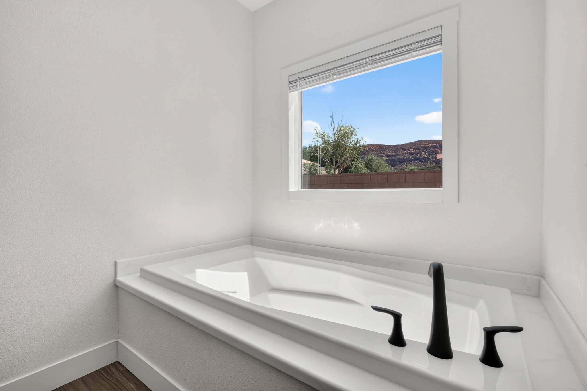 Built-in soaking tub with a white surround and matte black fixtures