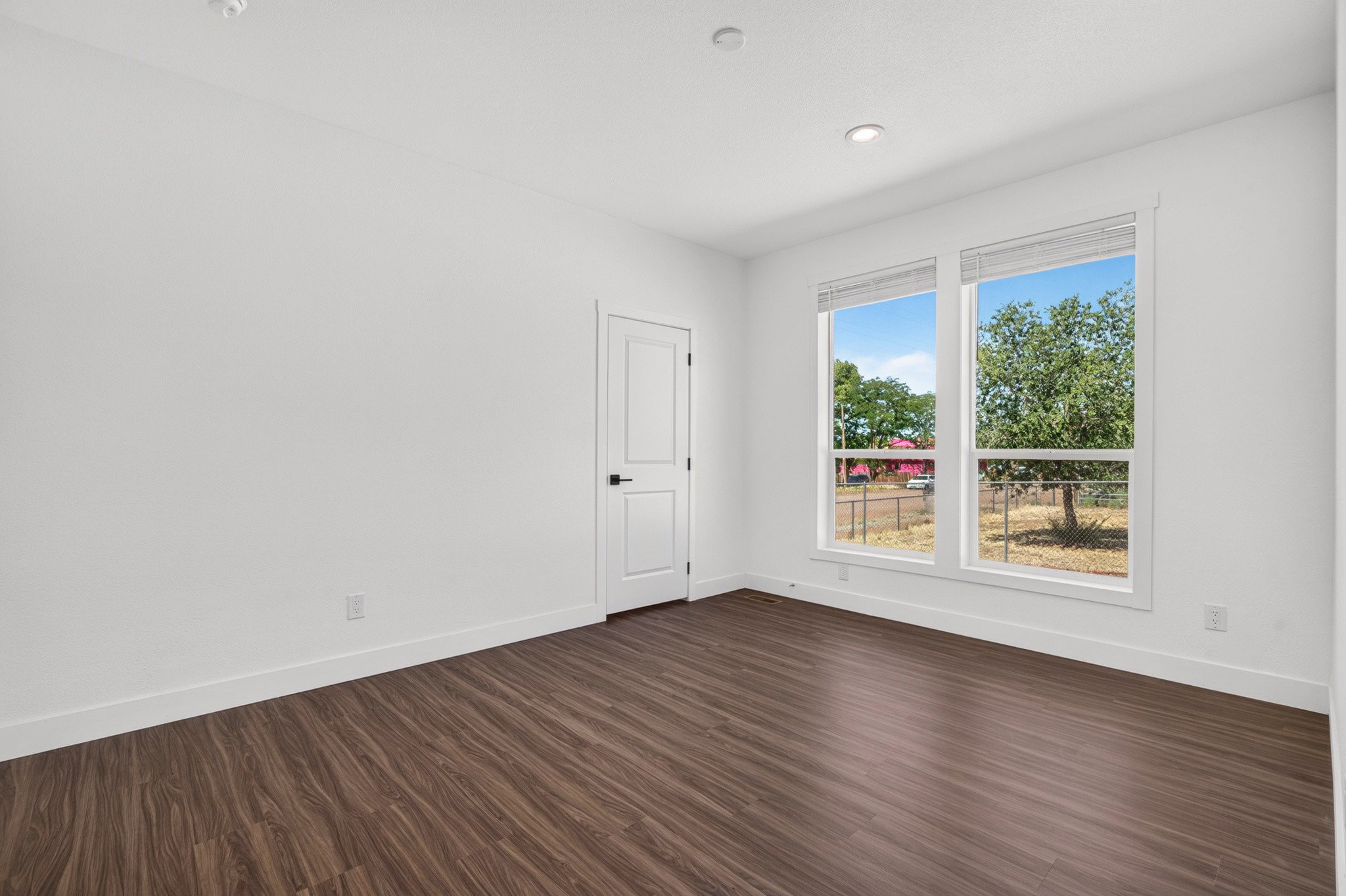 Bright interior space featuring wood-finish flooring, two large windows, white trim, and recessed lighting
