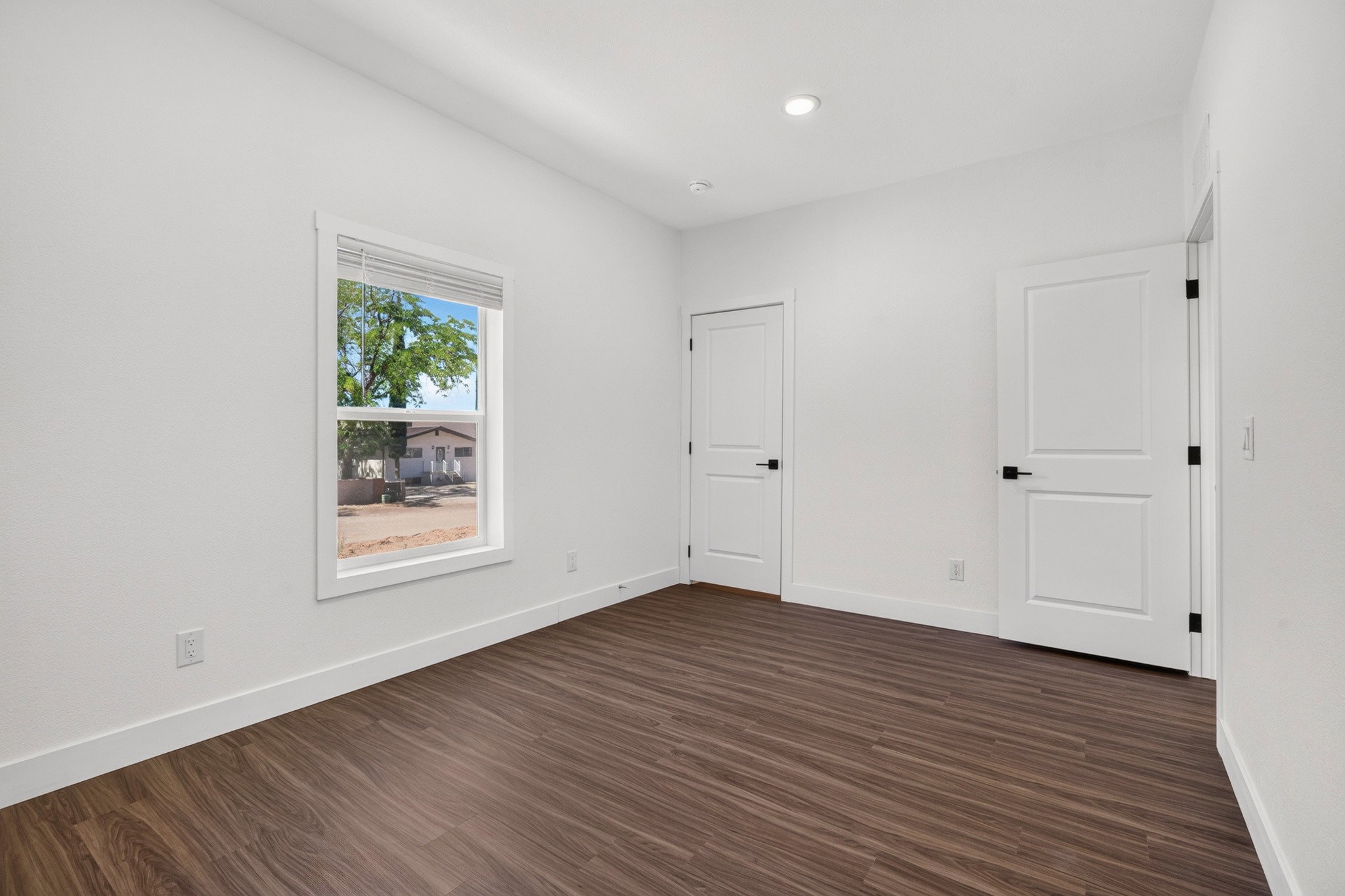 Interior room featuring wood-finish flooring, crisp white walls, and a recessed ceiling light